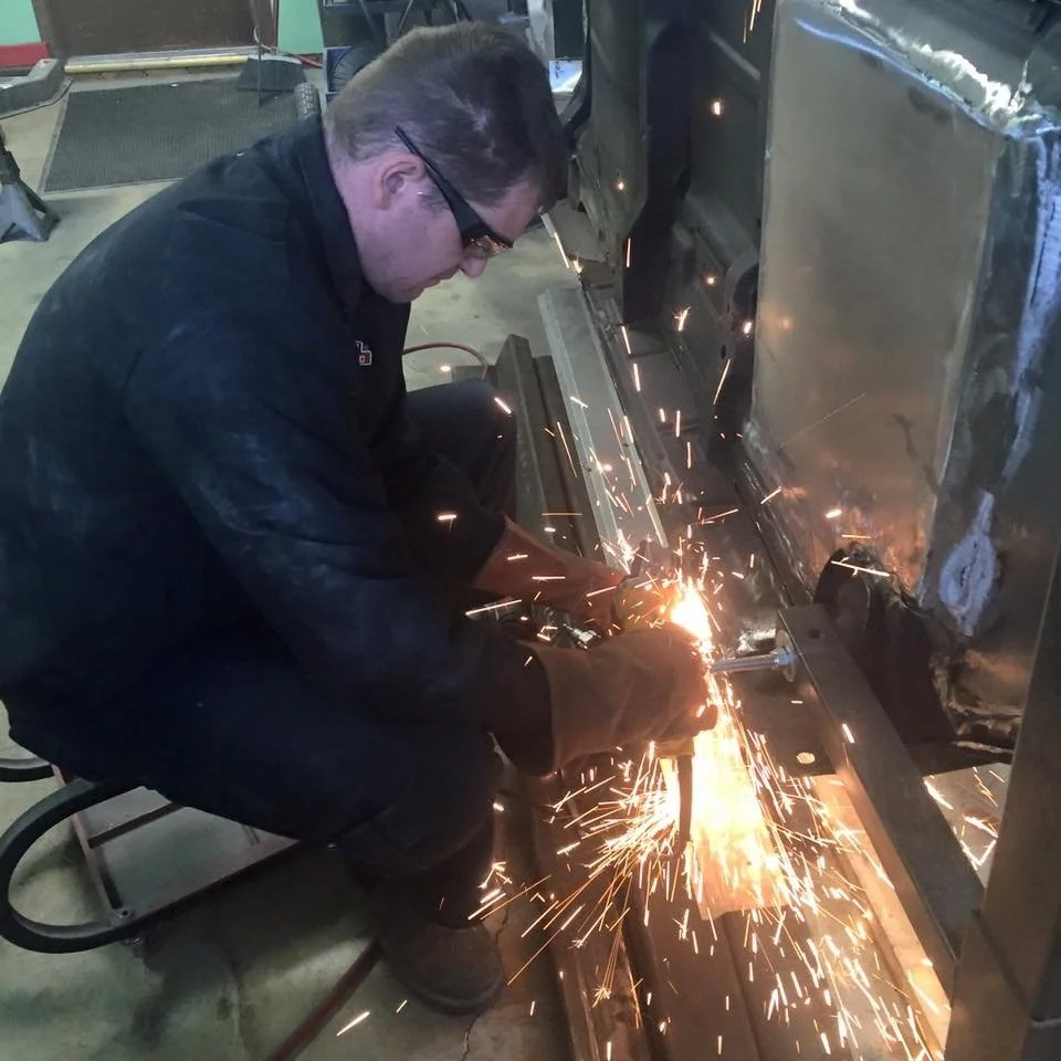 A person welding metal with sparks flying in a workshop.