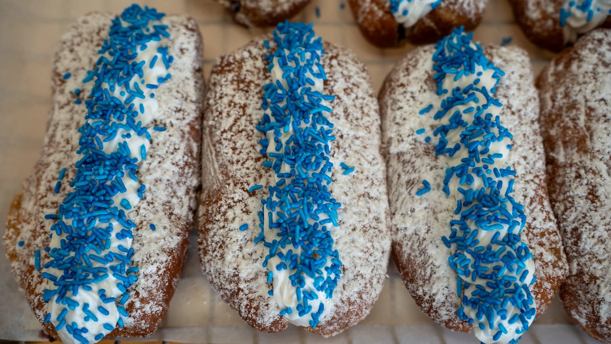 Three iced pastries sprinkled with powdered sugar and topped with blue sprinkles.