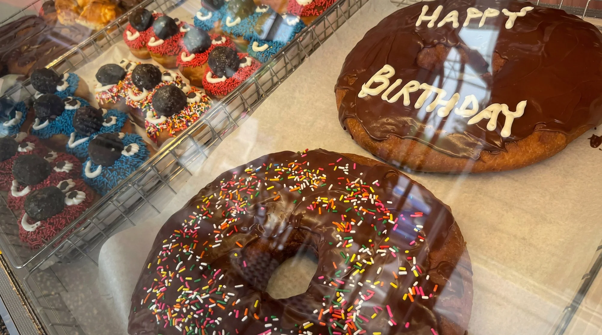 Belly busters oversized donuts, chocolate with sprinkles and Happy Birthday messaging