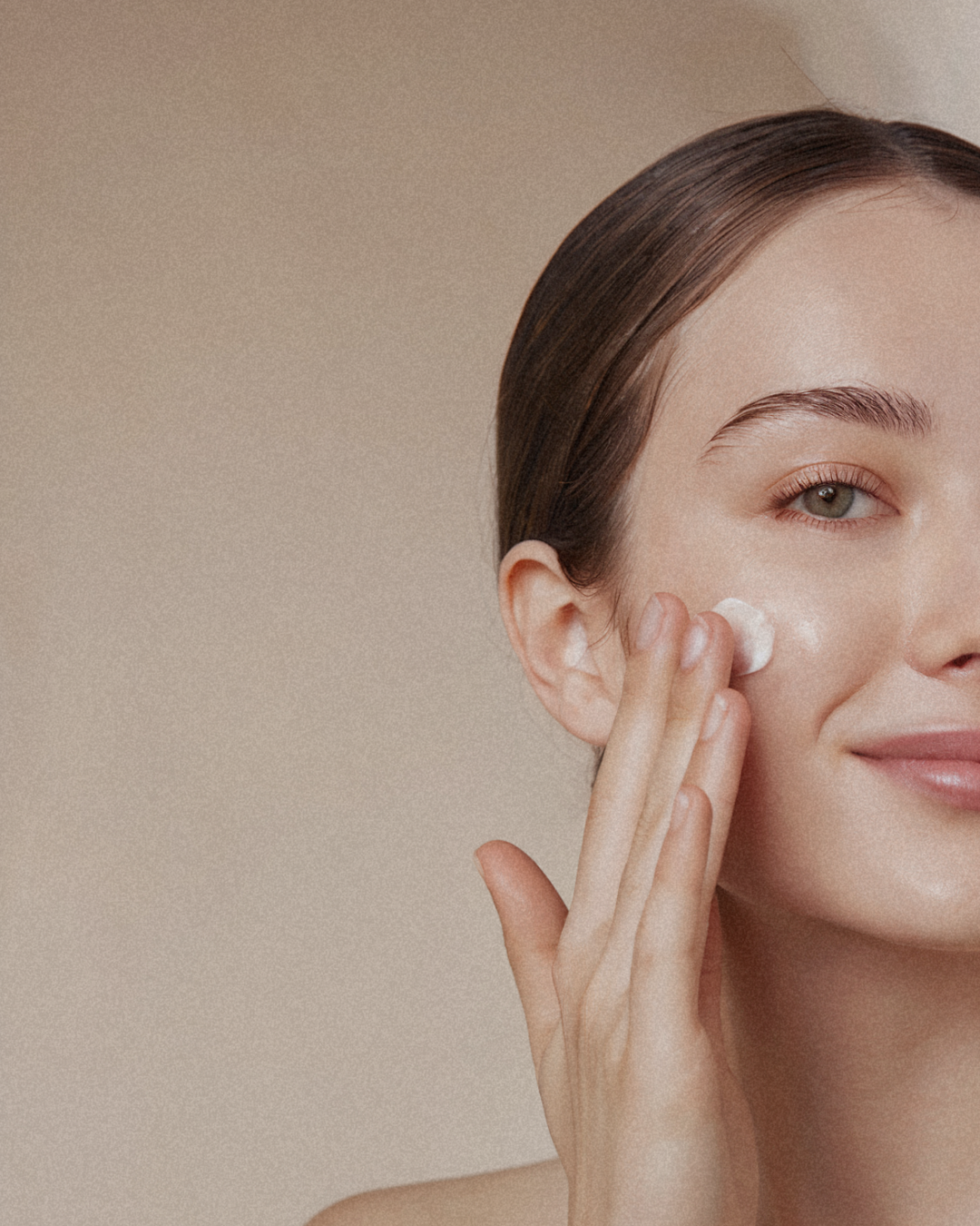 Une femme appliquant de la crème sur sa joue.