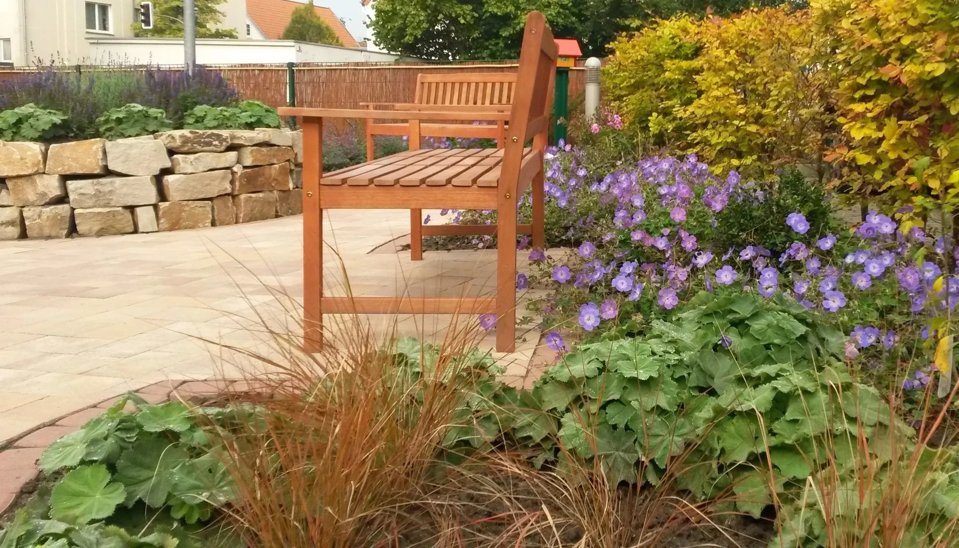 Privatgarten mit Sitzbank, Staudenbepflanzung und gepflasterter Fläche