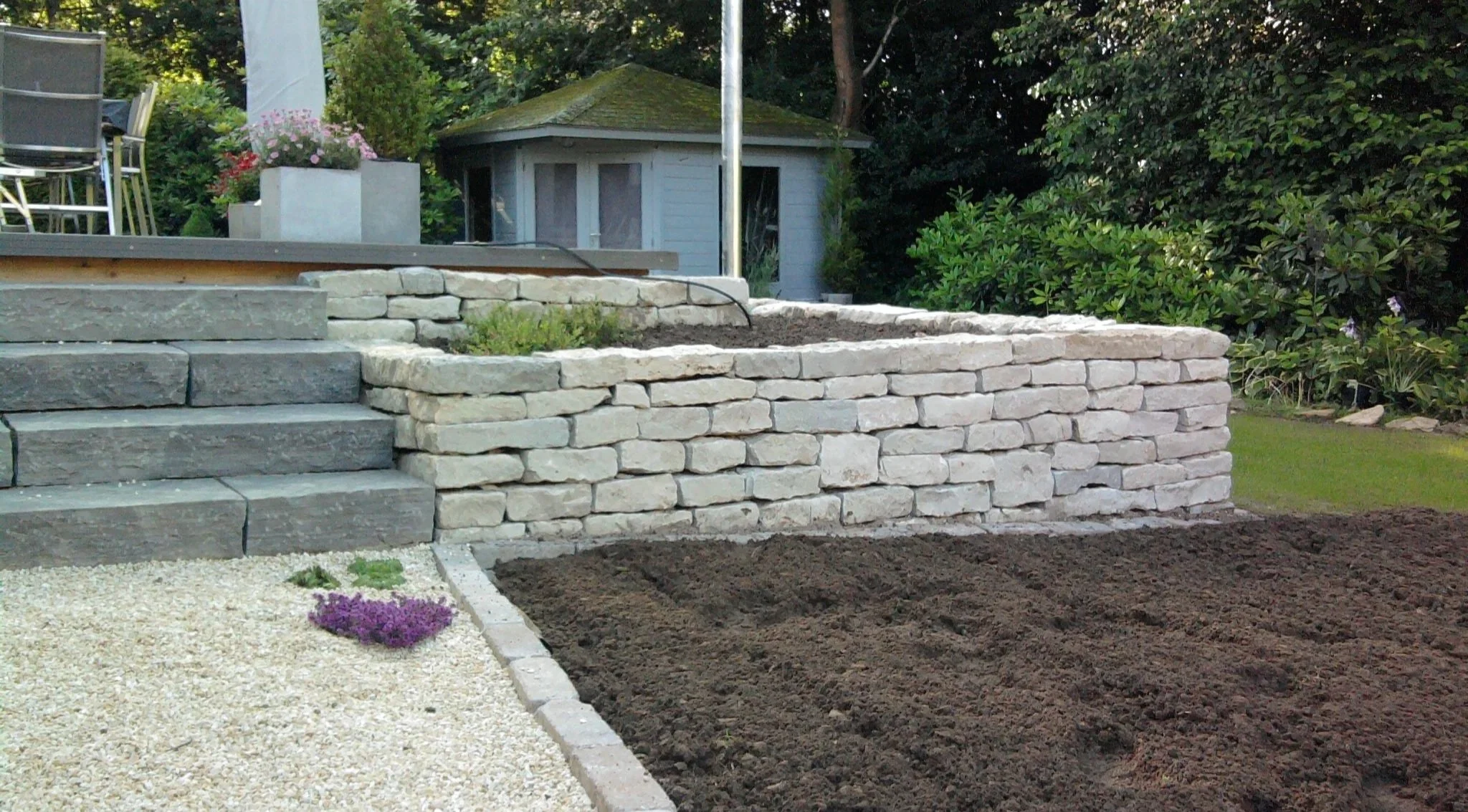 Natursteinmauer mit Gartentreppe in moderner Gartenanlage