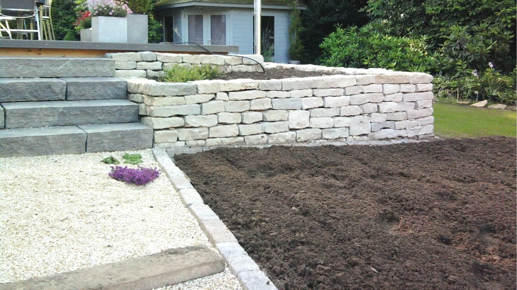 Gartengestaltung mit Trockenmauer, Steinstufen und Kiesweg