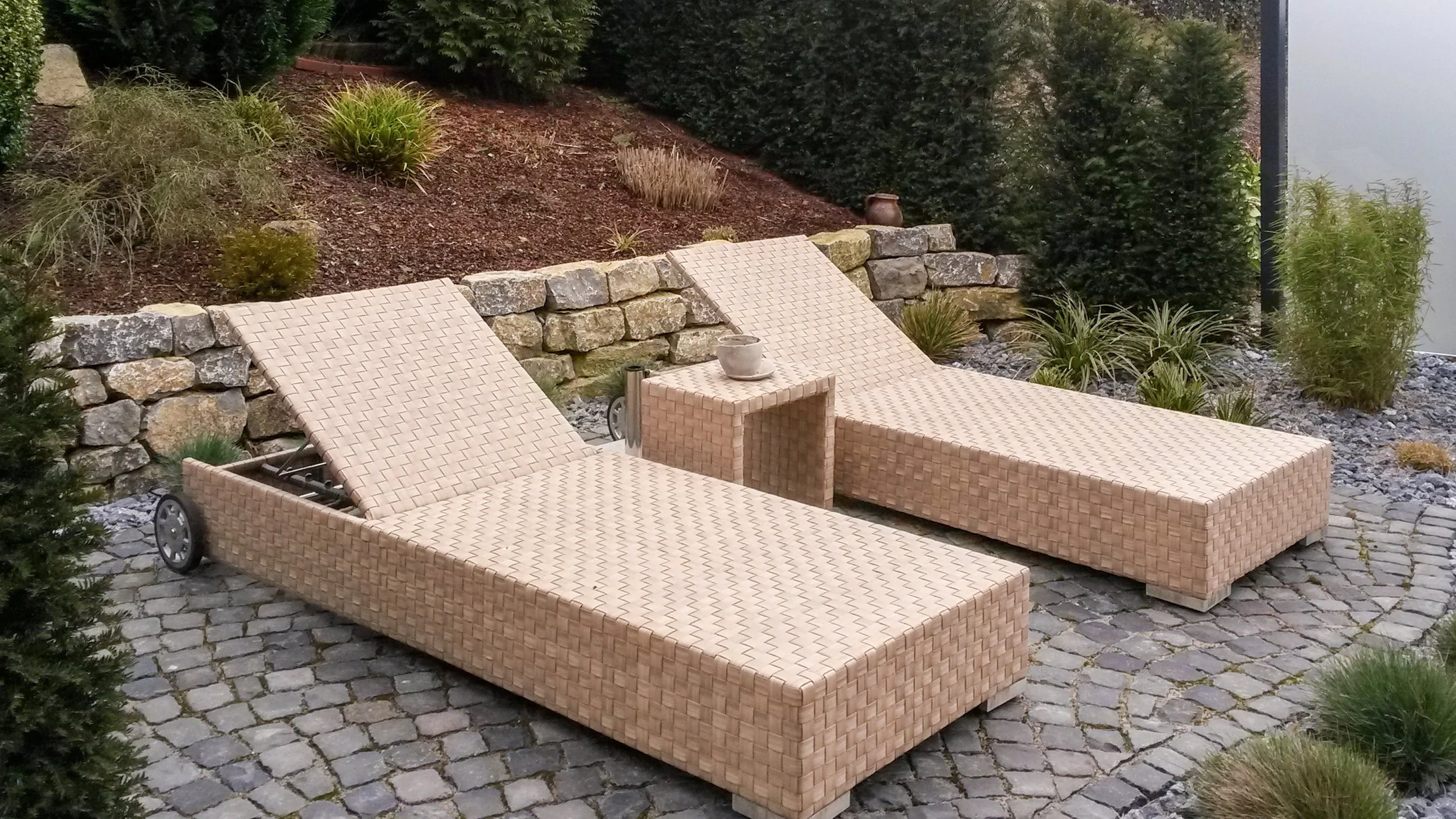 Moderne Gartenliegen mit Beistelltisch auf gepflasterter Terrasse in Privatgarten