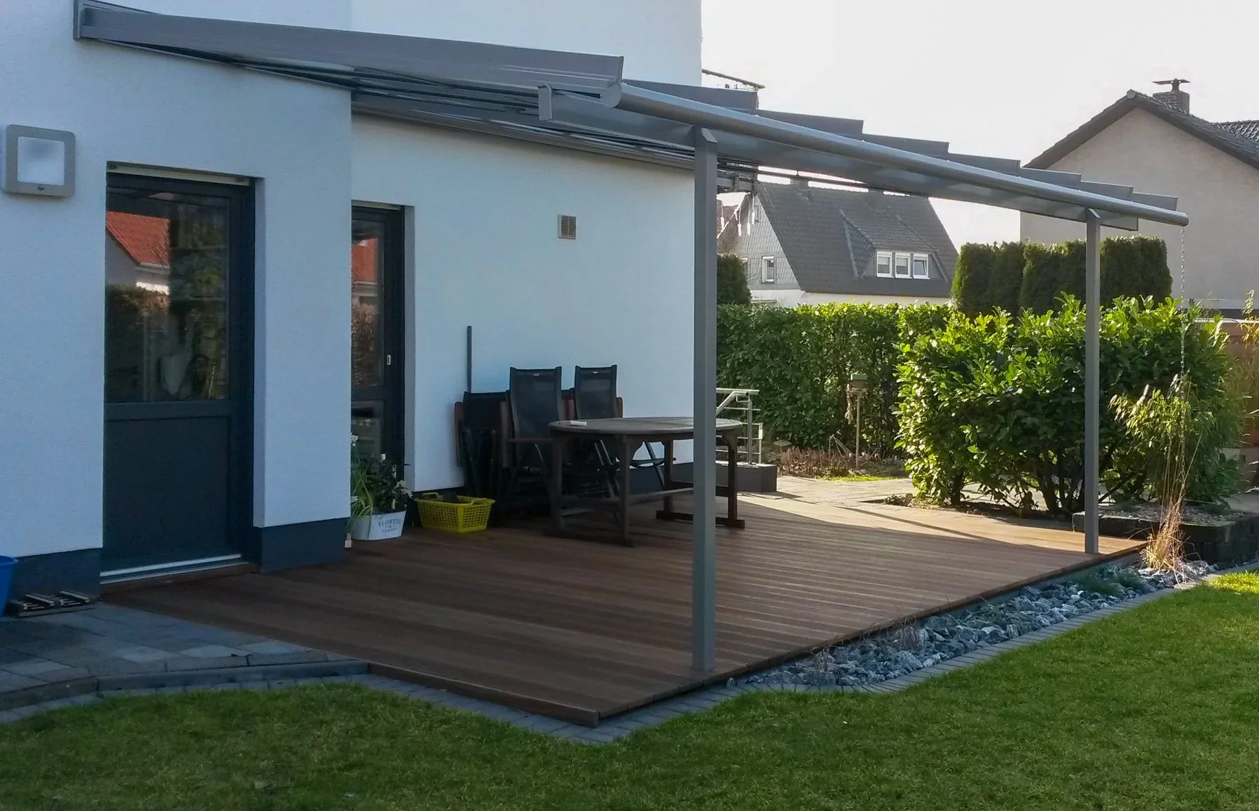 Moderne Terrasse mit Holzbelag und Gartenanlage am Einfamilienhaus