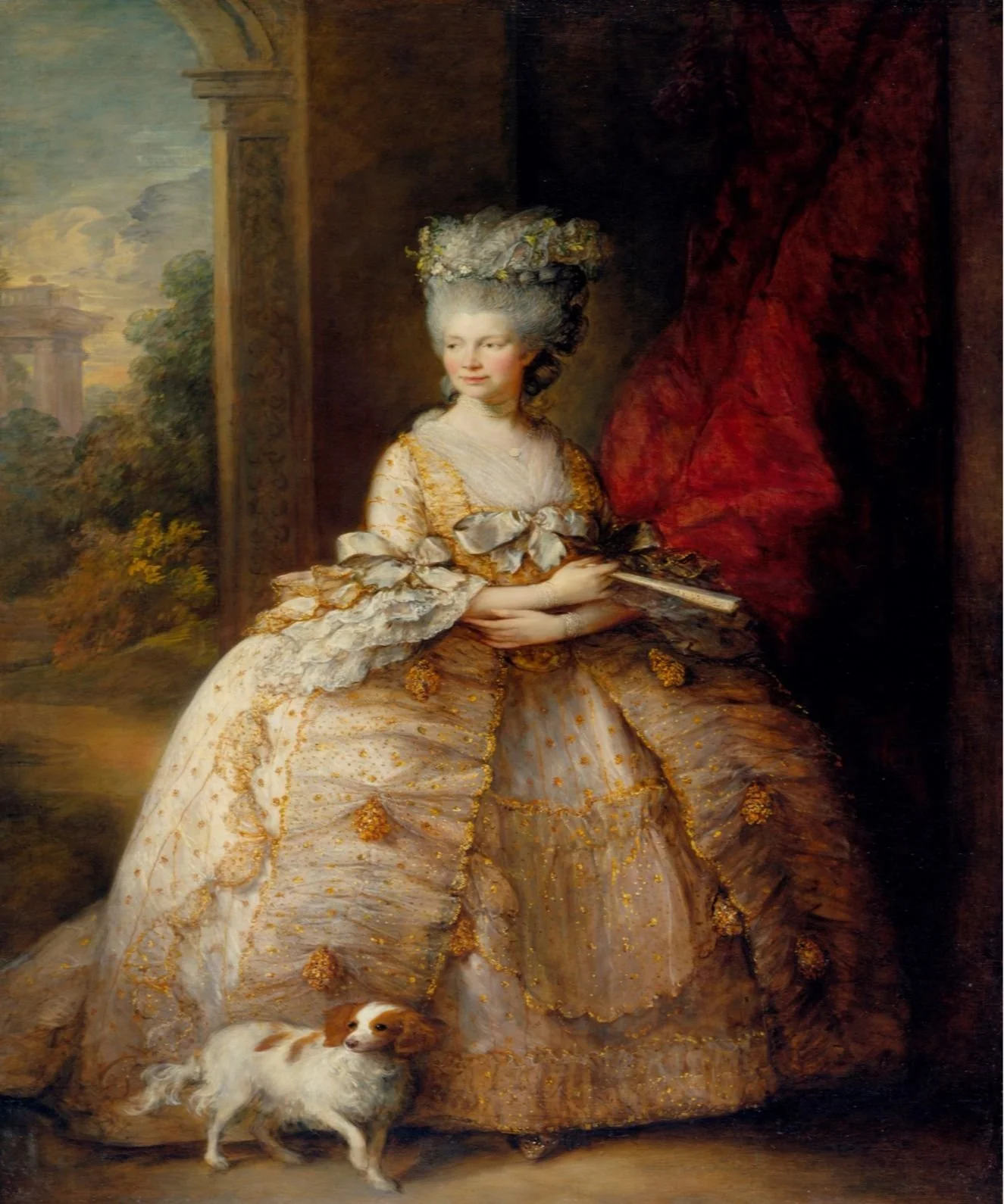 Queen Charlotte of England, painted in 1781 by Thomas Gainsborough. The Queen wears an elaborate cream and ochre dress with full skirts. In the front is a small dog, perhaps a Cavalier King Charles.