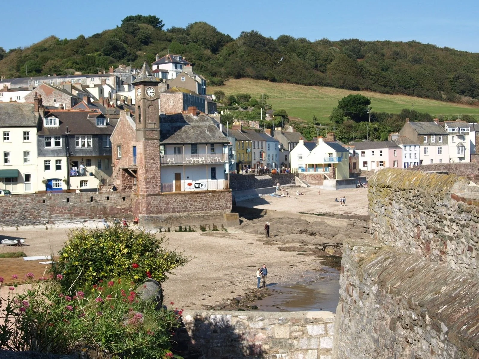 Twin villages Kingsand and Cawsand photographed fro the west on a sunny day. The grassy slopes of the Minnadew Brakes - part of the country park are seen behind the jumble of cottages.