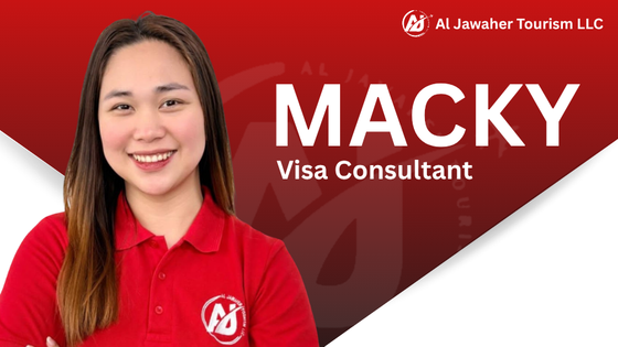 Macky, a visa consultant, wearing a red shirt with company logo, standing in front of a red and white background with company branding.