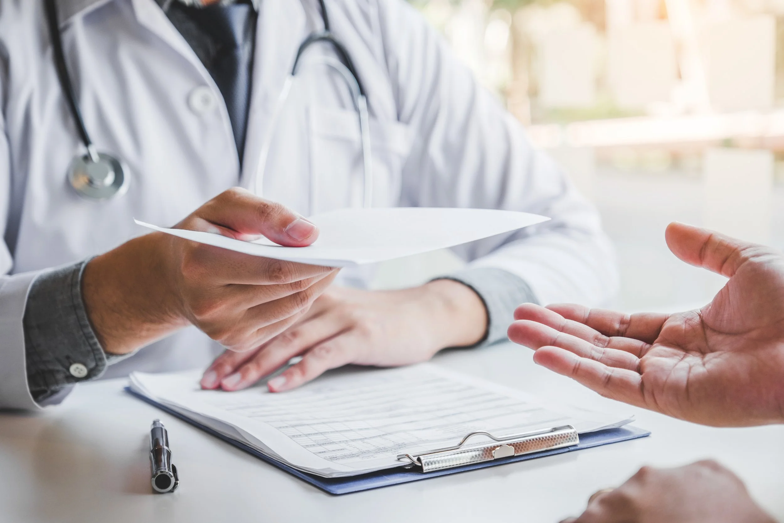 Doctor hands a lab slip to a patient across a table