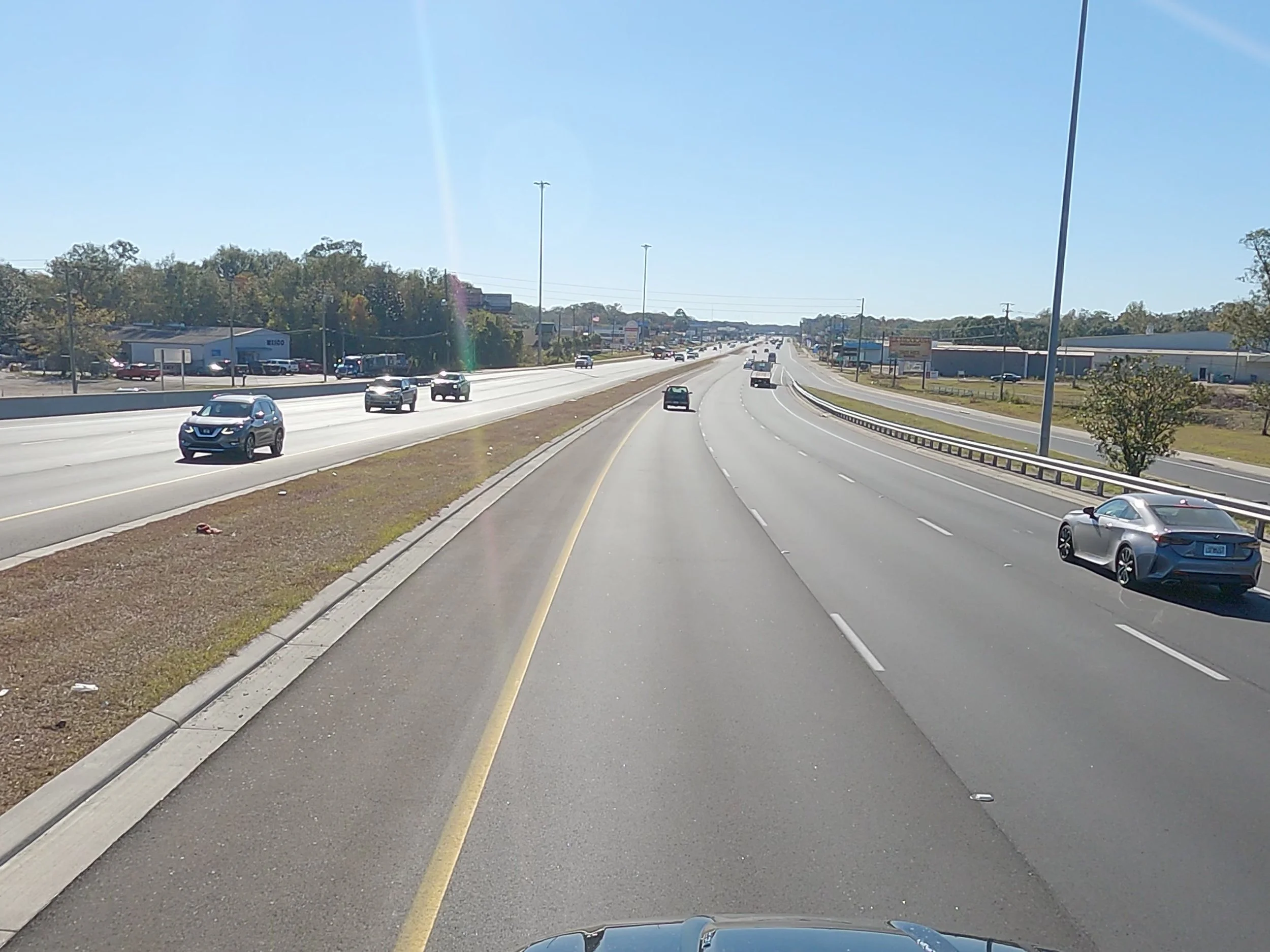 A multi-lane highway with several cars traveling in both directions on a sunny day.