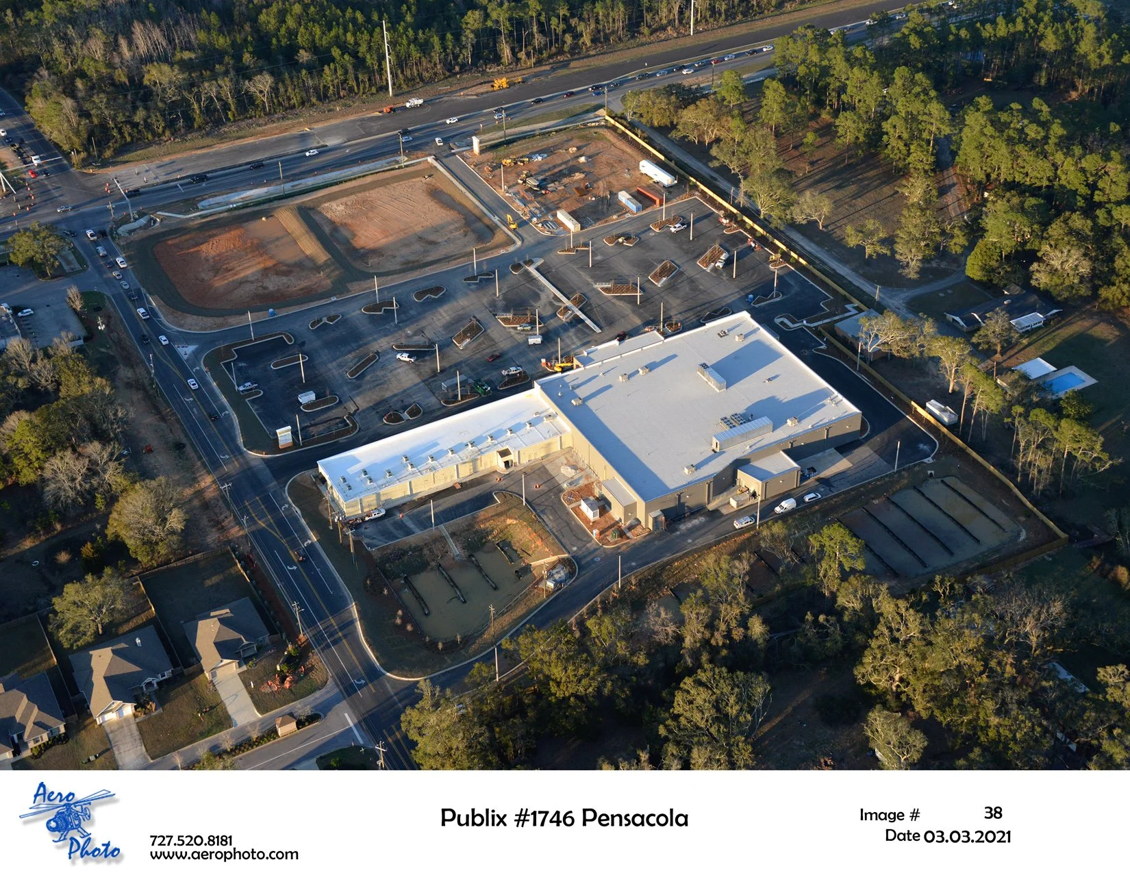 An aerial view of a Publix grocery store in Pensacola, Florida, with parking lot, surrounding trees, and adjacent residential neighborhood.
