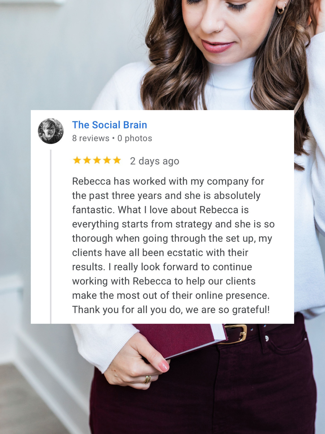 A woman with brown hair wearing a white top and maroon pants is holding a maroon notebook or journal. A review card is overlaid on the image, containing a five-star review for 'The Social Brain' service, praising Rebecca’s work with clients for her thoroughness and strategy.