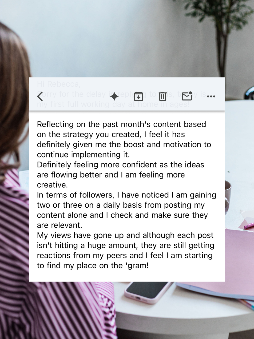 Screenshot of an email testimonial from a happy client, with a blurred background of a person at a desk with a smartphone, notebook, and pen.