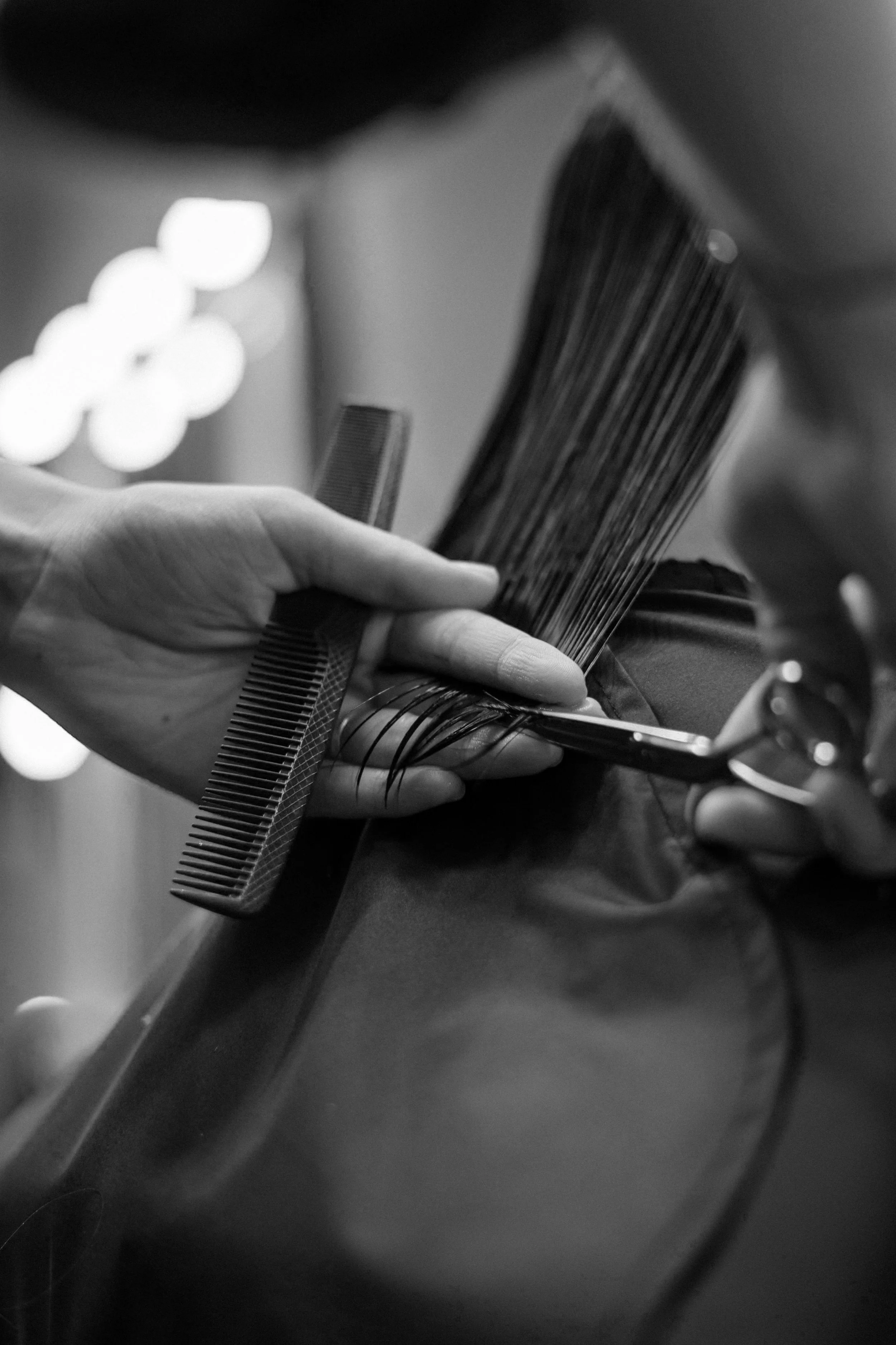 A person getting a haircut, with a comb and scissors, in black and white.
