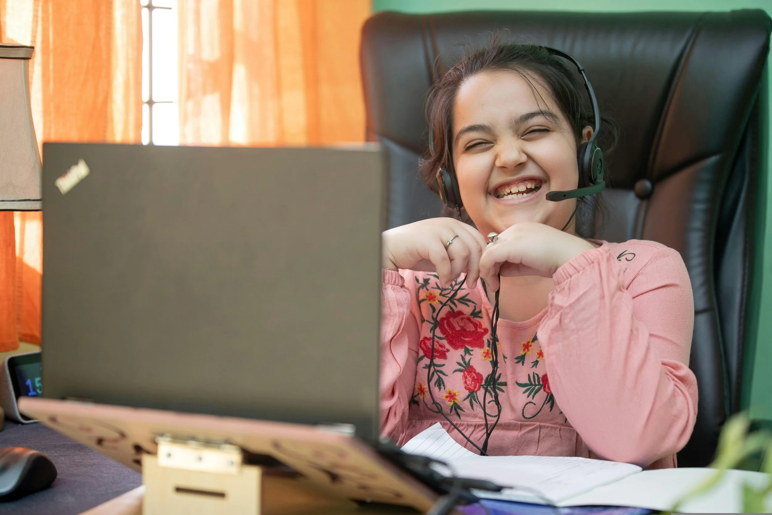 A child smiling at her laptop