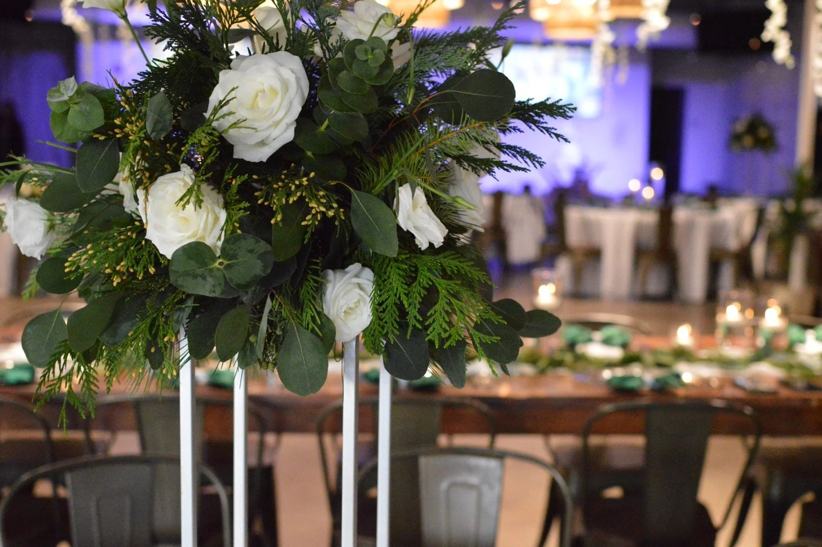 Close-up of a floral centerpiece with white roses, greenery, and eucalyptus.