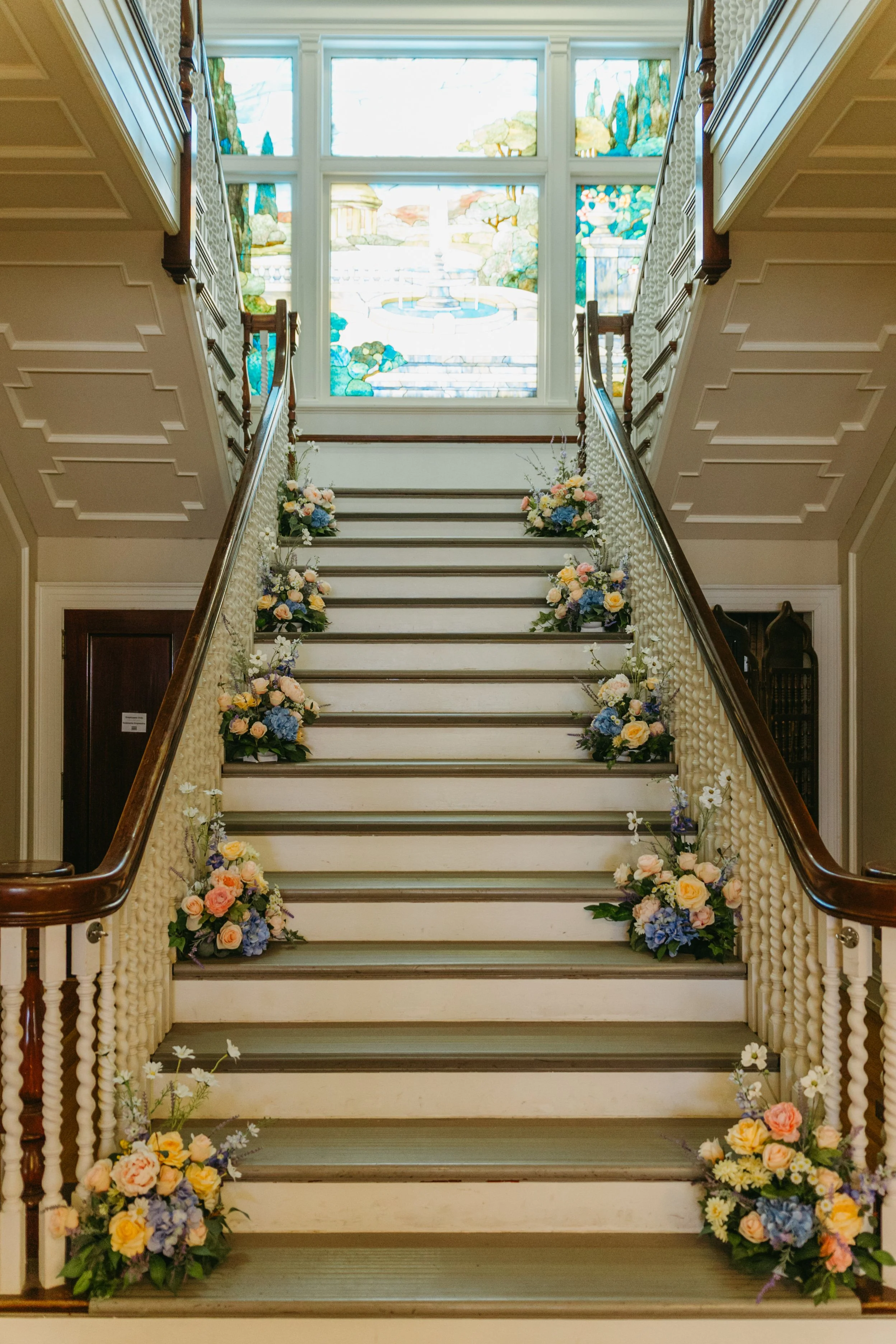 Indoor staircase decorated with flower arrangements on each step.