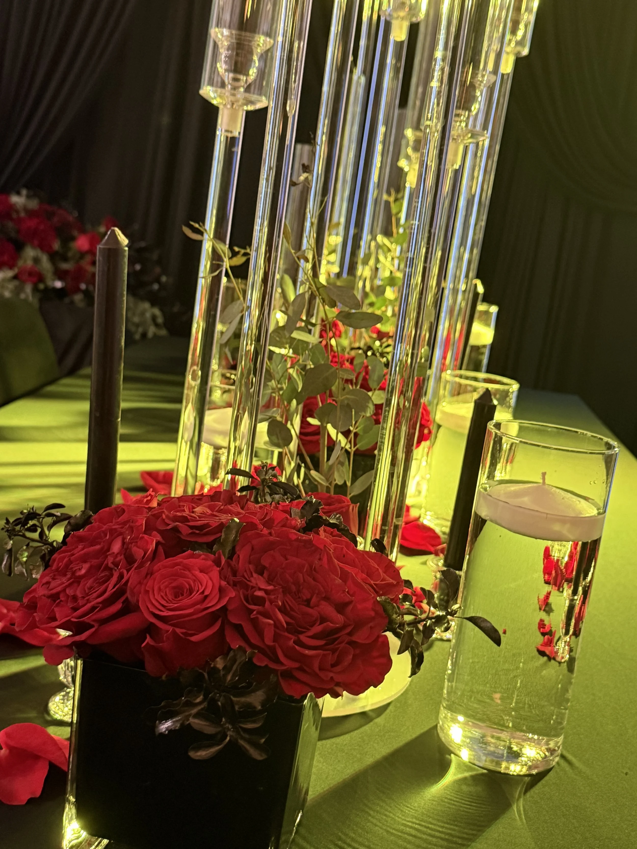 A table centerpiece with red roses and greenery.