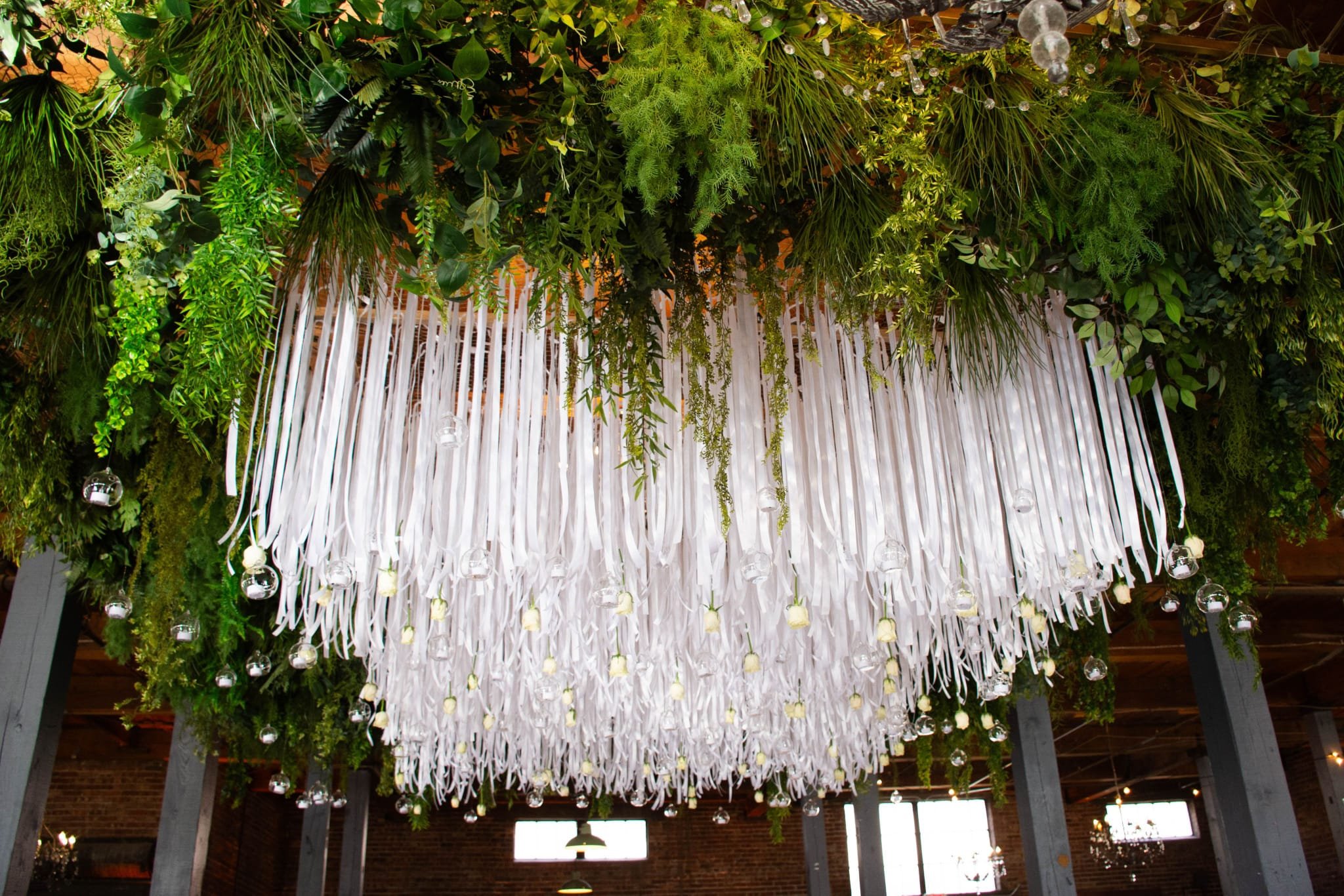 Decorative ceiling with lush green foliage and white ribbons arrangement.