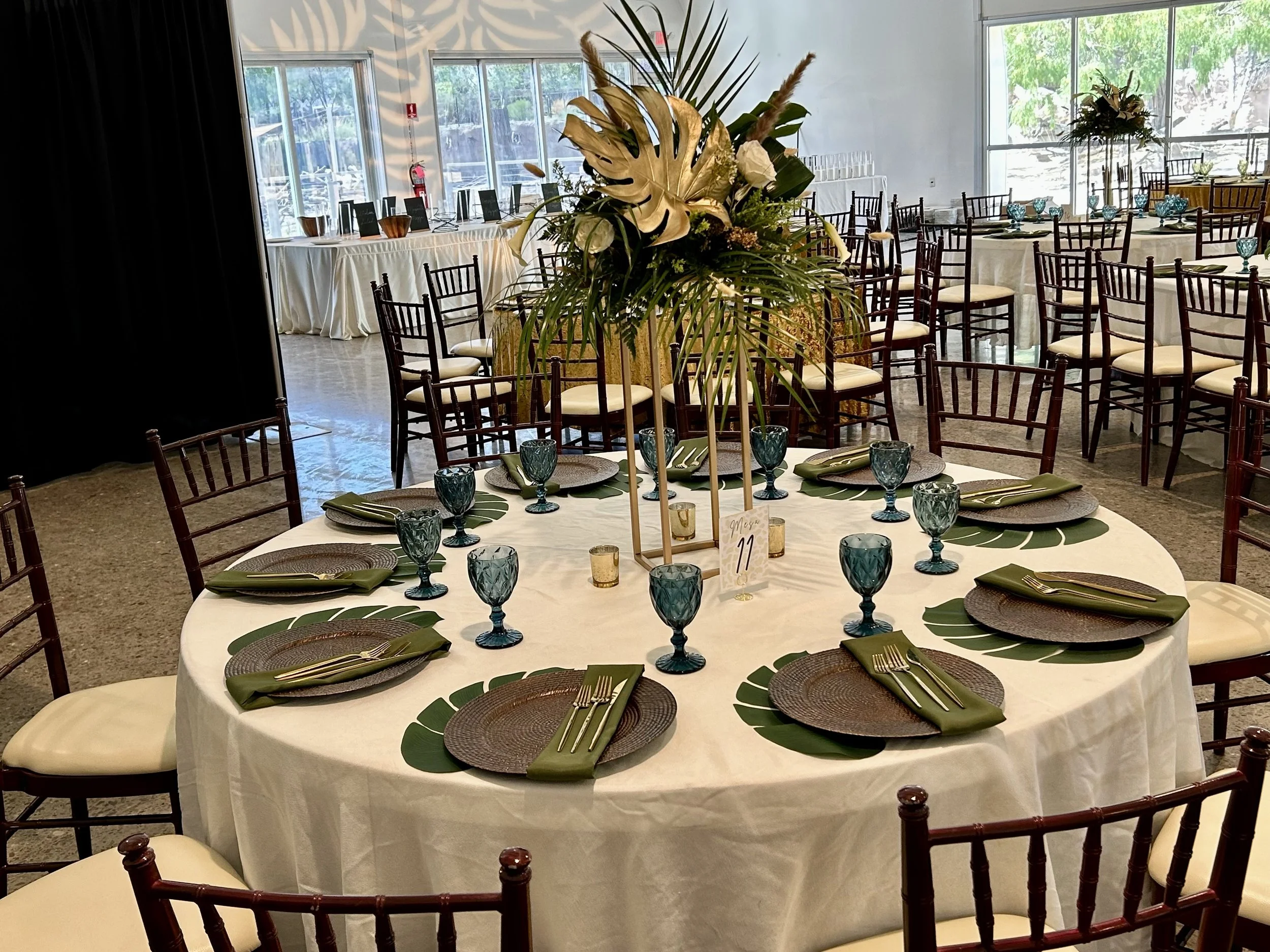 Round table set for a formal event with a white tablecloth, green and brown place settings.
