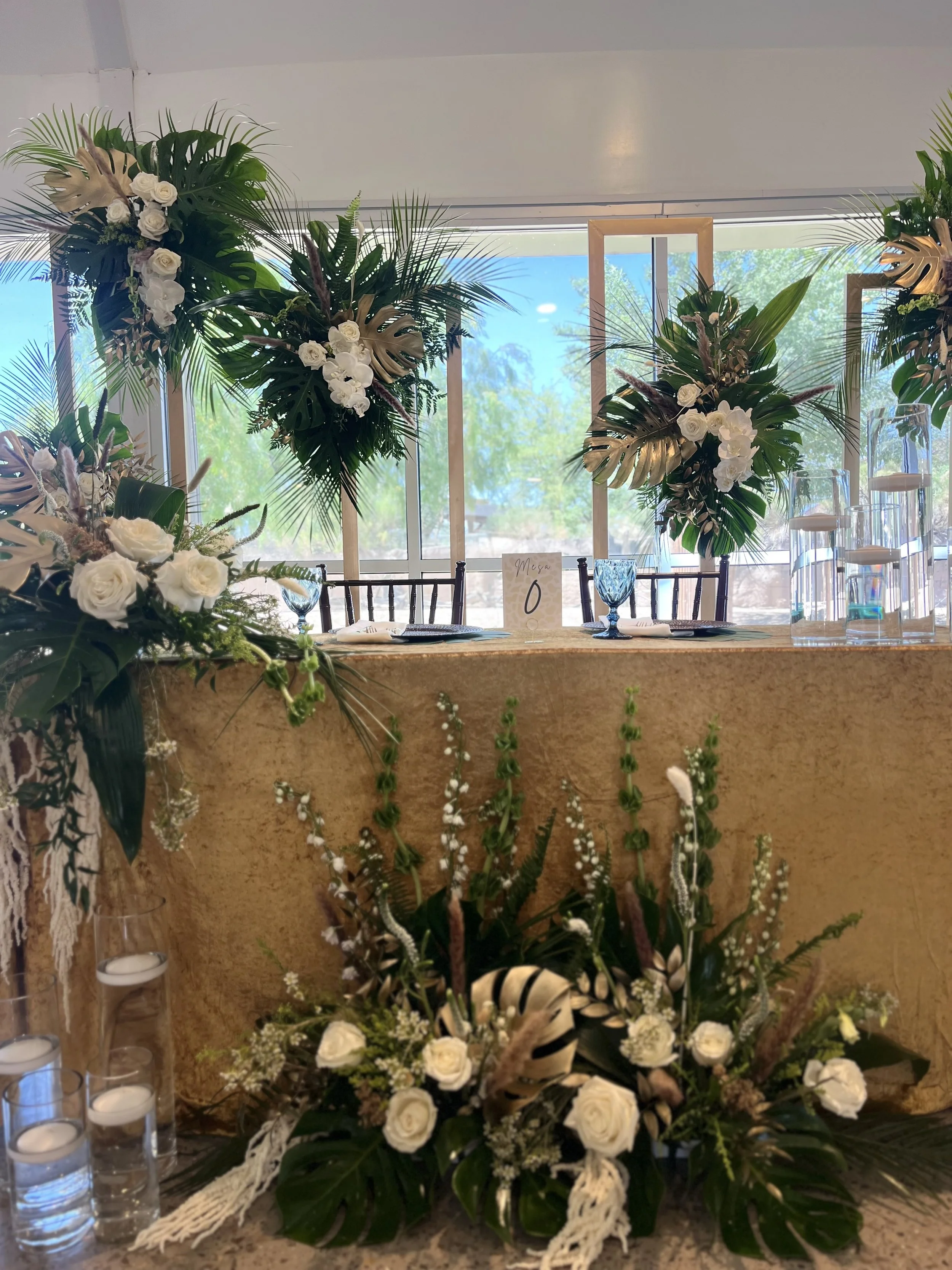 Decorated banquet table with tropical greenery.