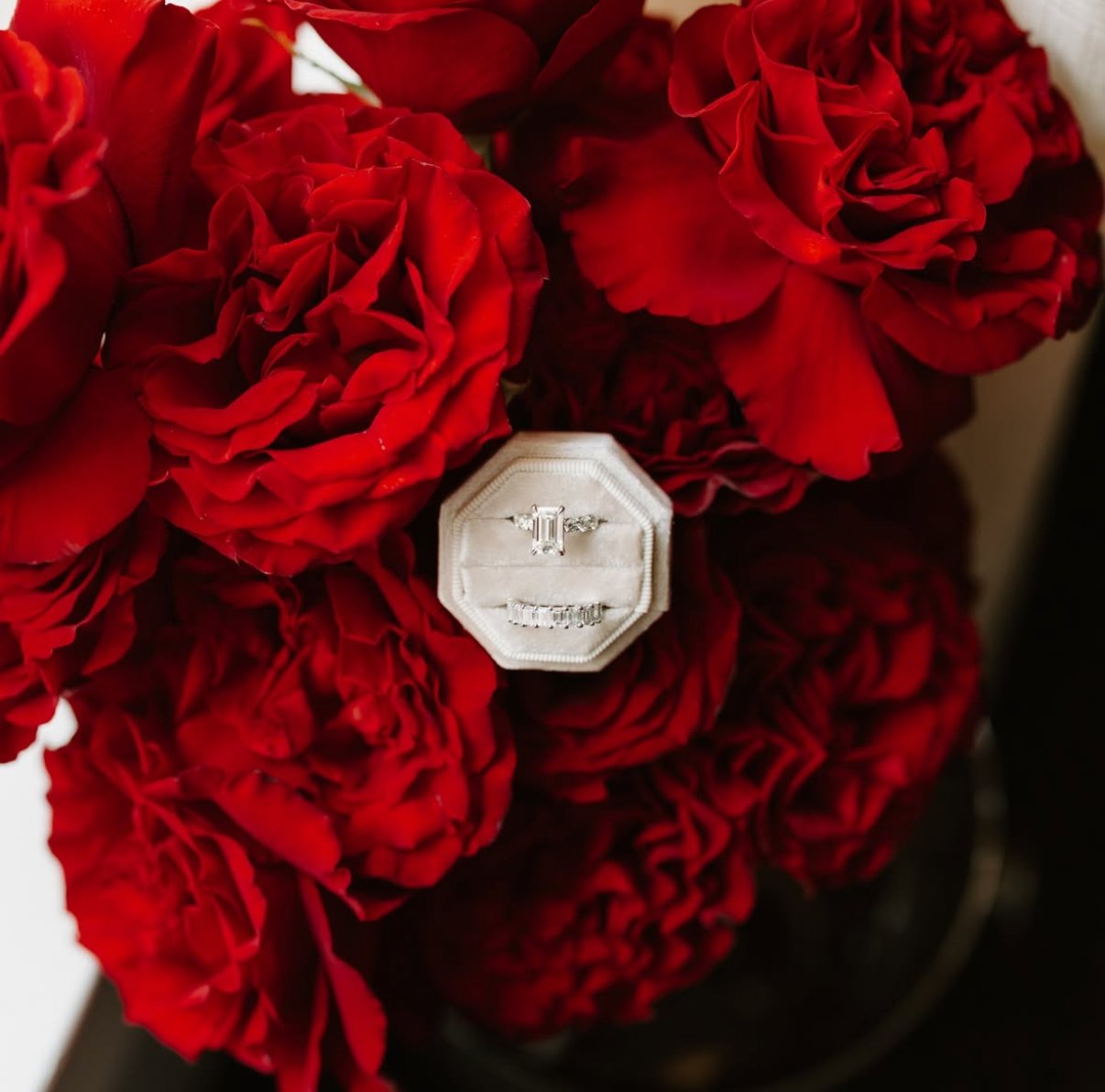 Red peony flowers with a silver engagement ring.