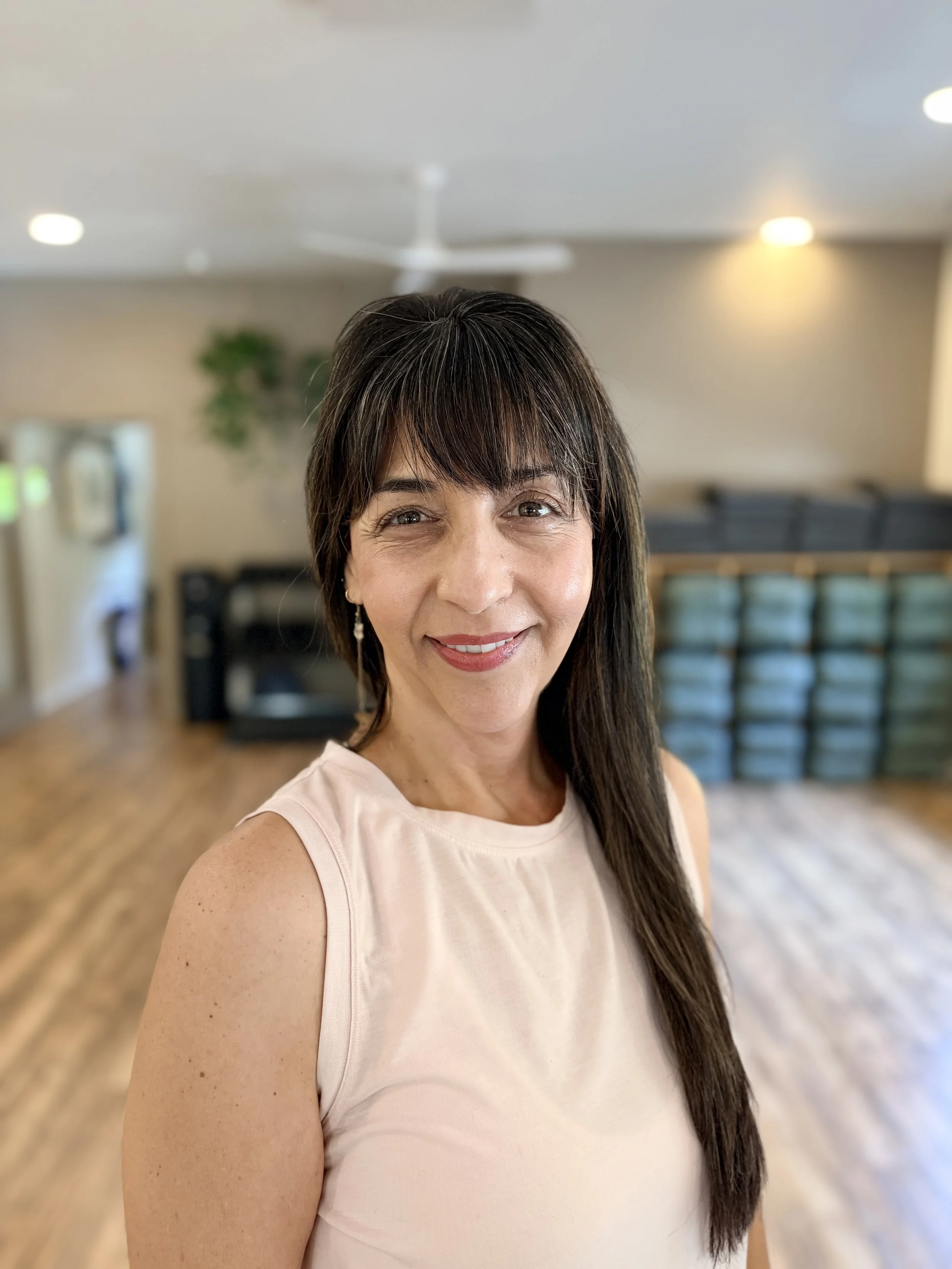 woman with brown hair smiling in a yoga studio