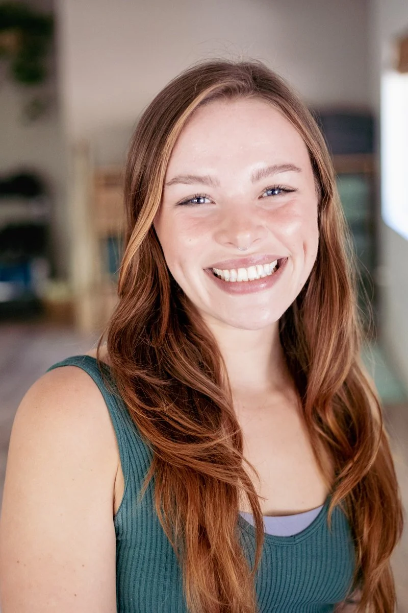 a blonde woman with a big smile and a ponytail inside a yoga studio