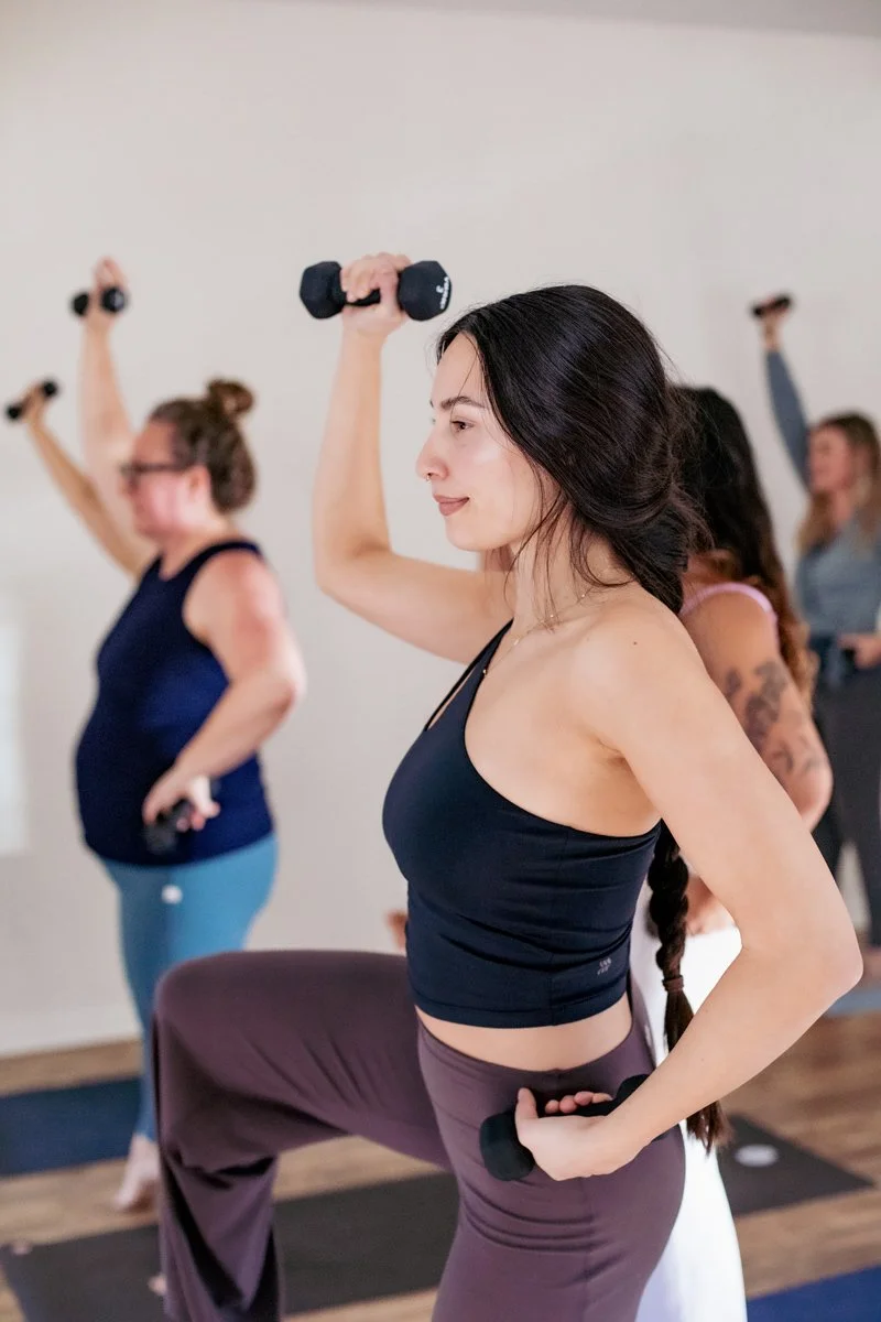 brunette woman doing yoga with weights