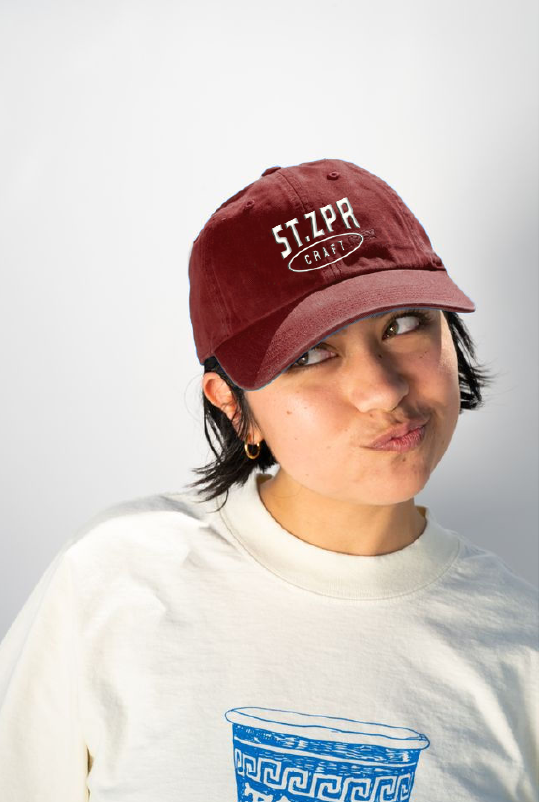 Woman wearing a red workwear baseball cap with a graphic print that read ST.SPR Craft