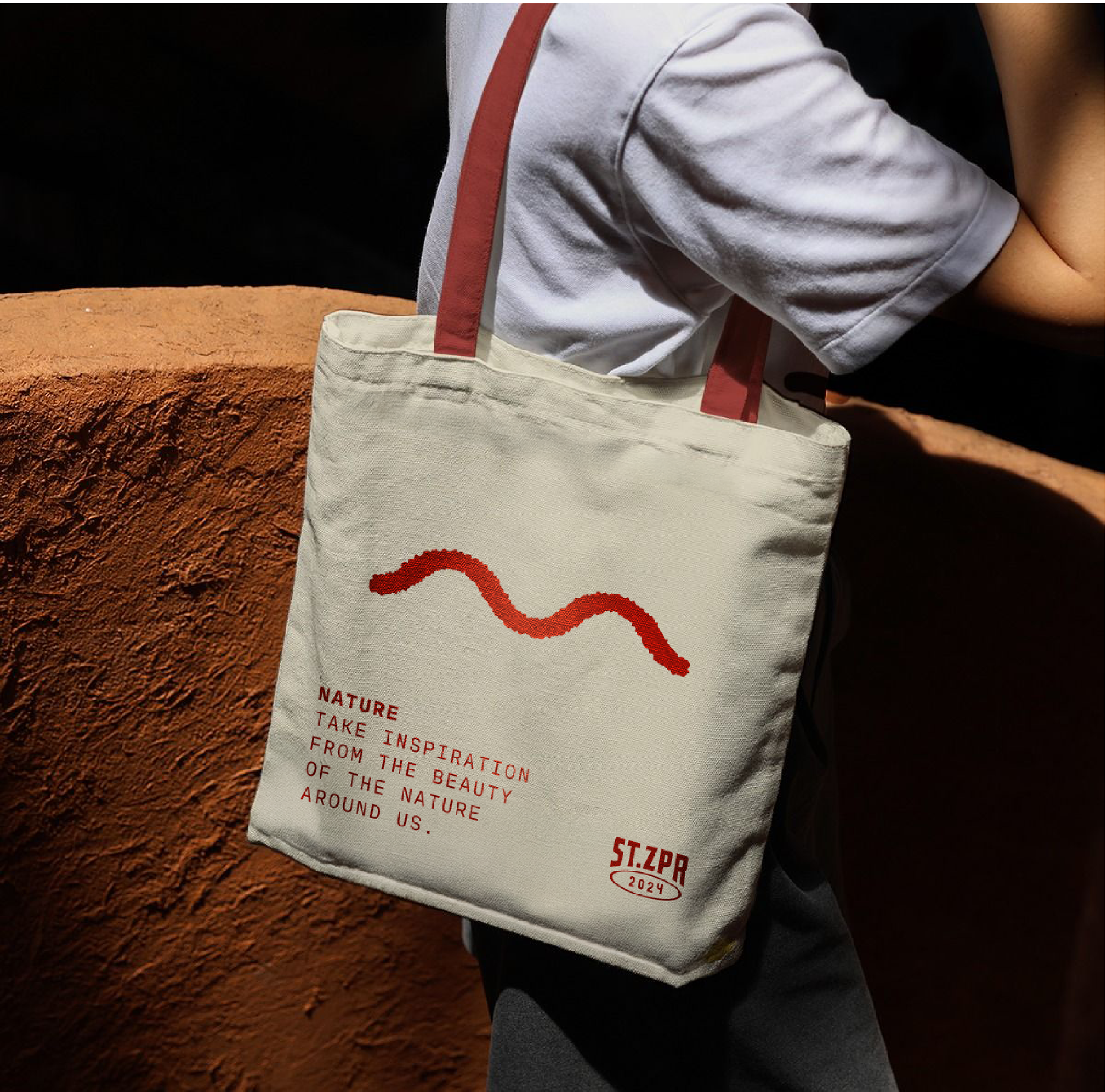 A tote bag branded in red studio zephyr colours with a nature icon on