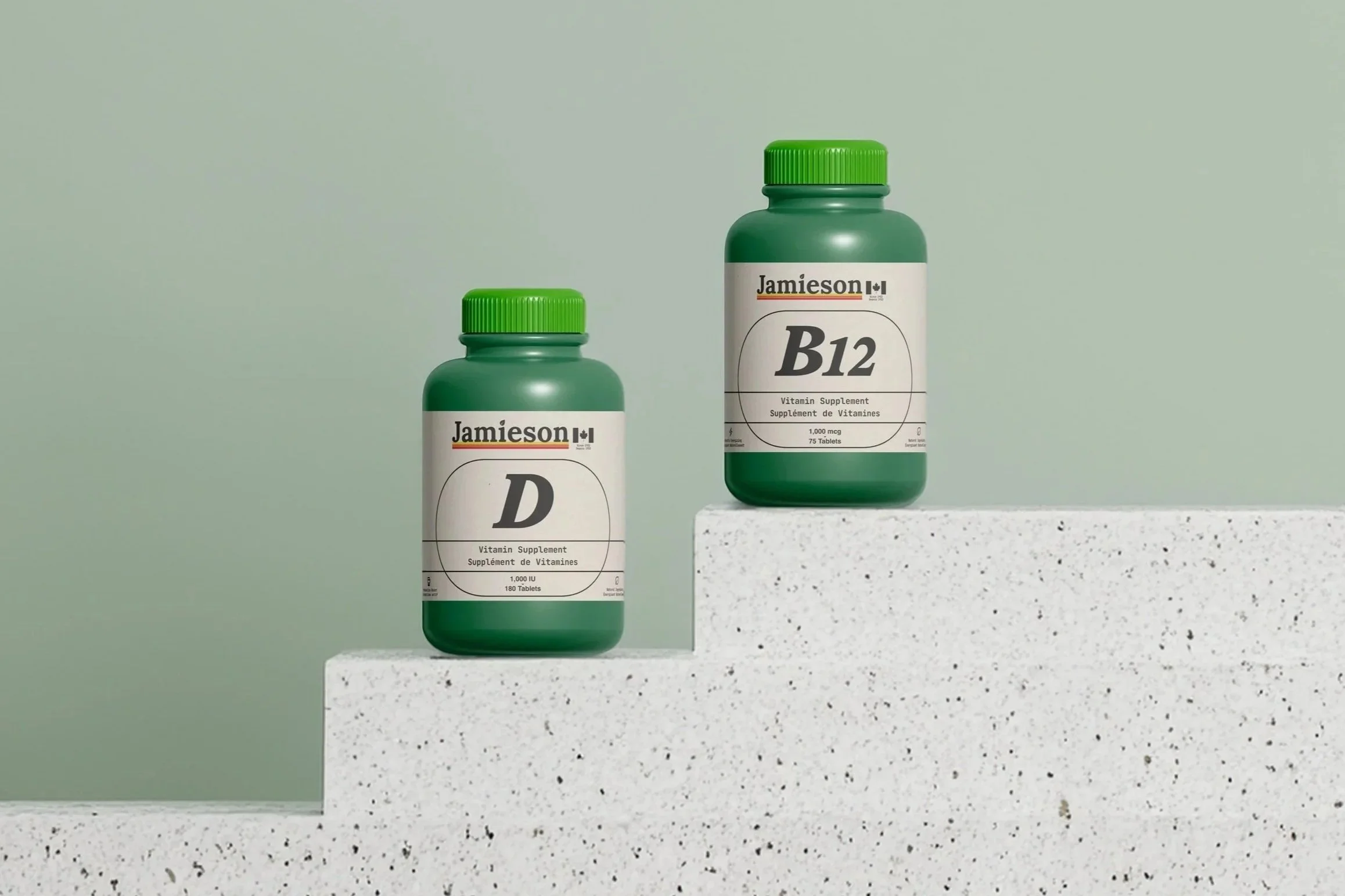 Jamieson Vitamin D and Vitamin B12 supplements in new premium packaging, styled by Kieren Dial on minimalist white concrete steps against a soft green background.