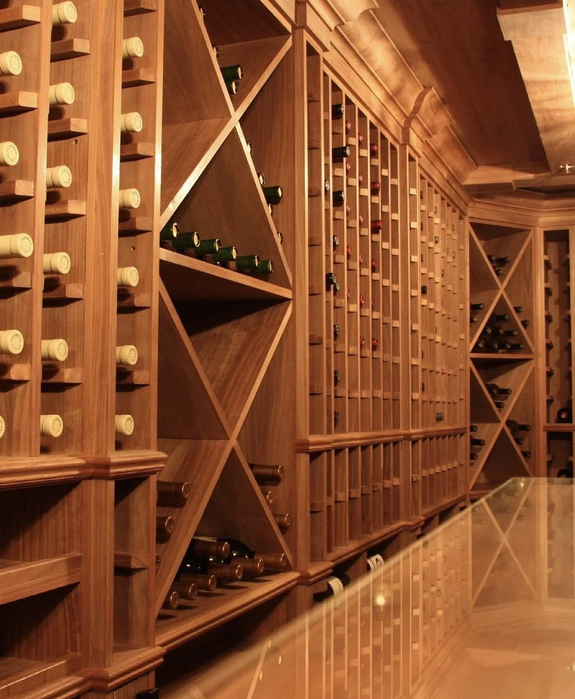 A wine cellar with wooden wine racks filled with bottles arranged horizontally.