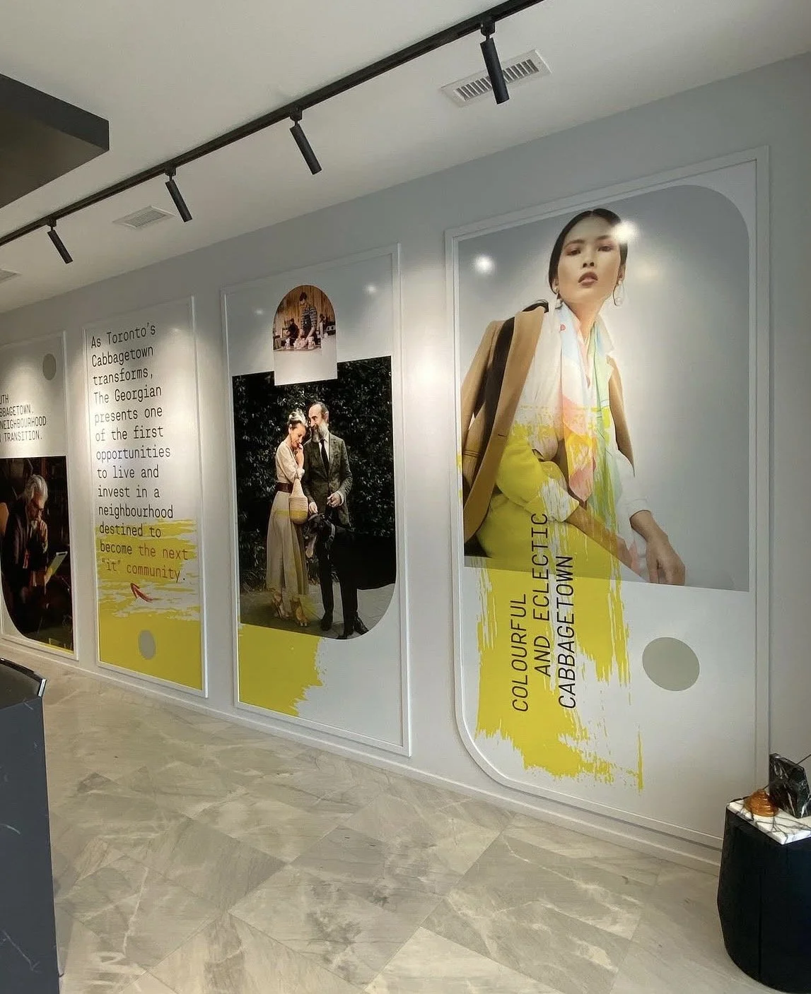 Large wall display with fashion photos and text about Toronto's Cabbagetown neighborhood, highlighting its transformation and community charm, featuring a woman with a backpack in one of the photos.