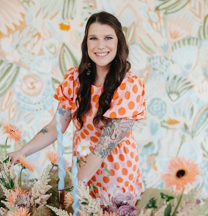 Taylor Doyle, CEO and Founder of Lance Craft, arranging florals in a colorful studio setting.