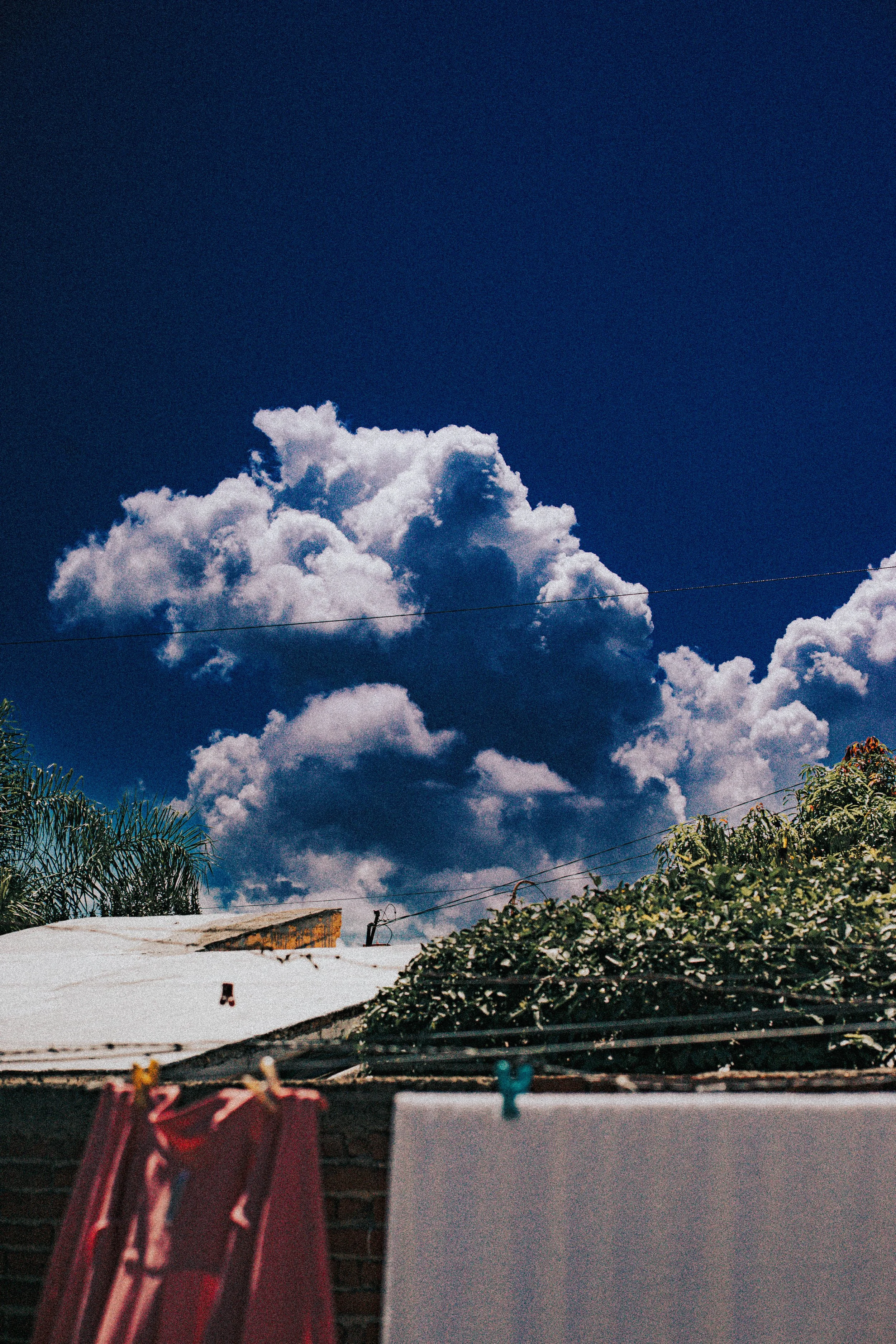 Cloudy sky above residential rooftops and laundry hanging on a clothesline.