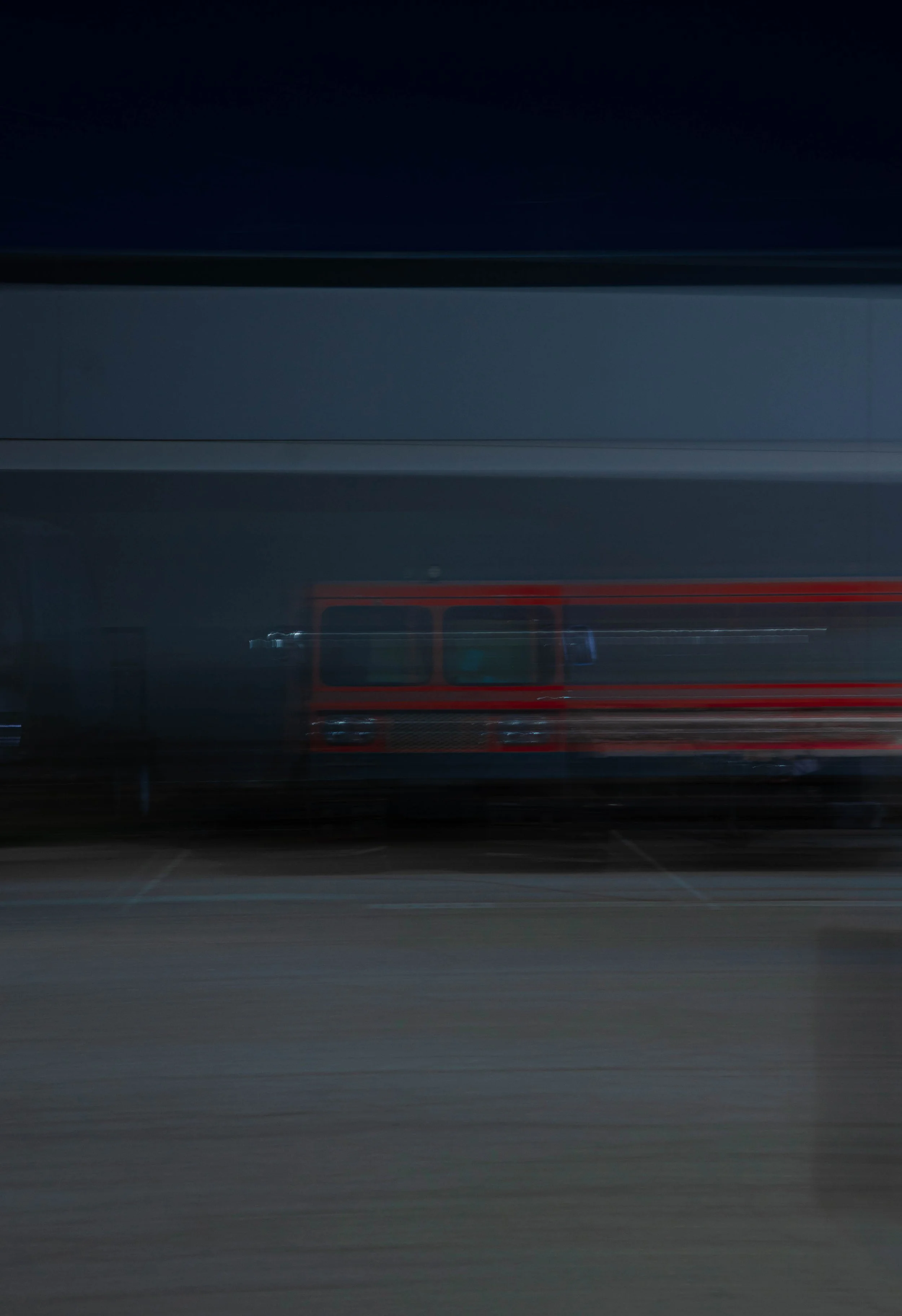 Blurred image of a parked fire truck at night with a dark sky and a building in the background.