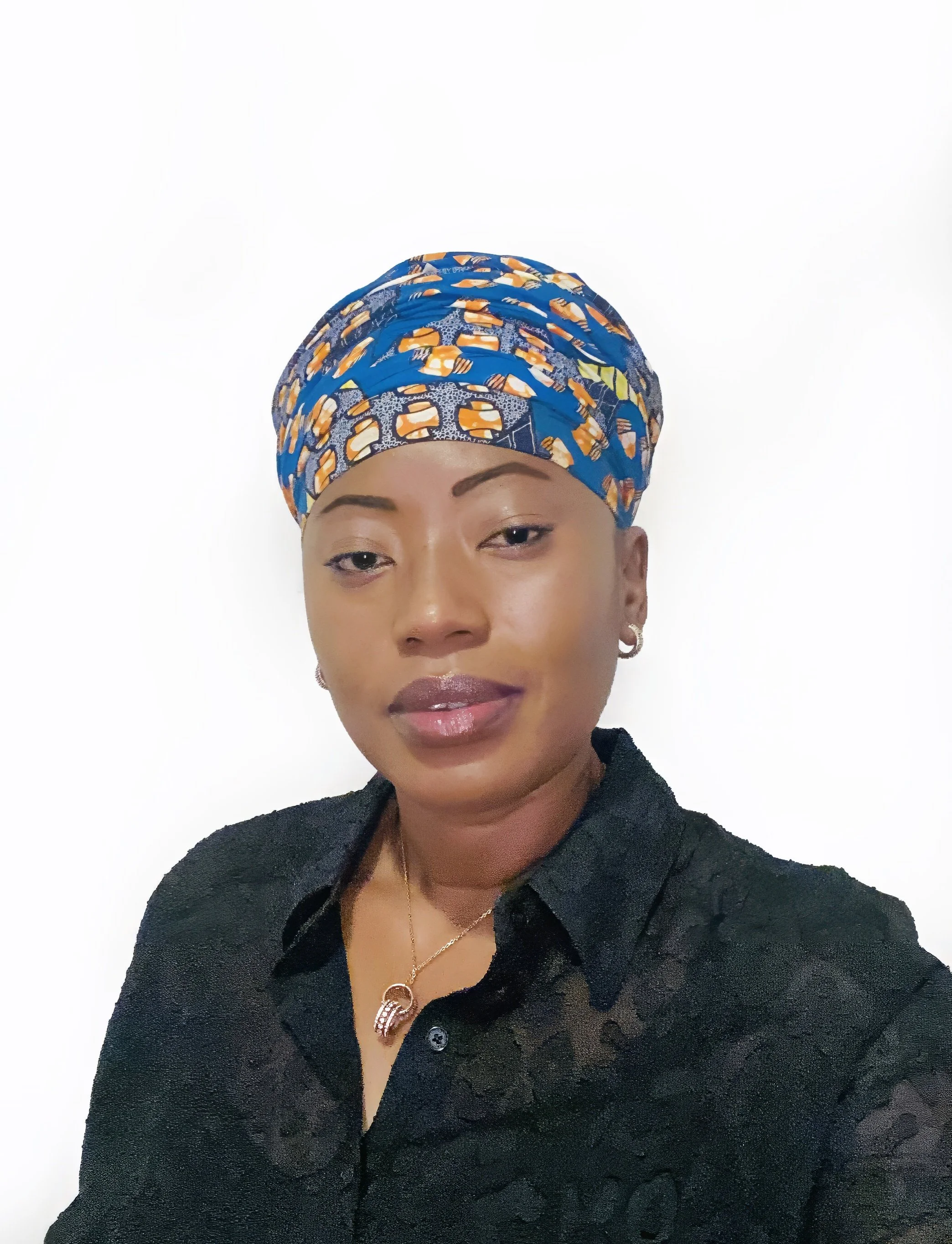 A woman wearing a colorful headscarf, earrings, and a black blouse, standing against a plain white background.