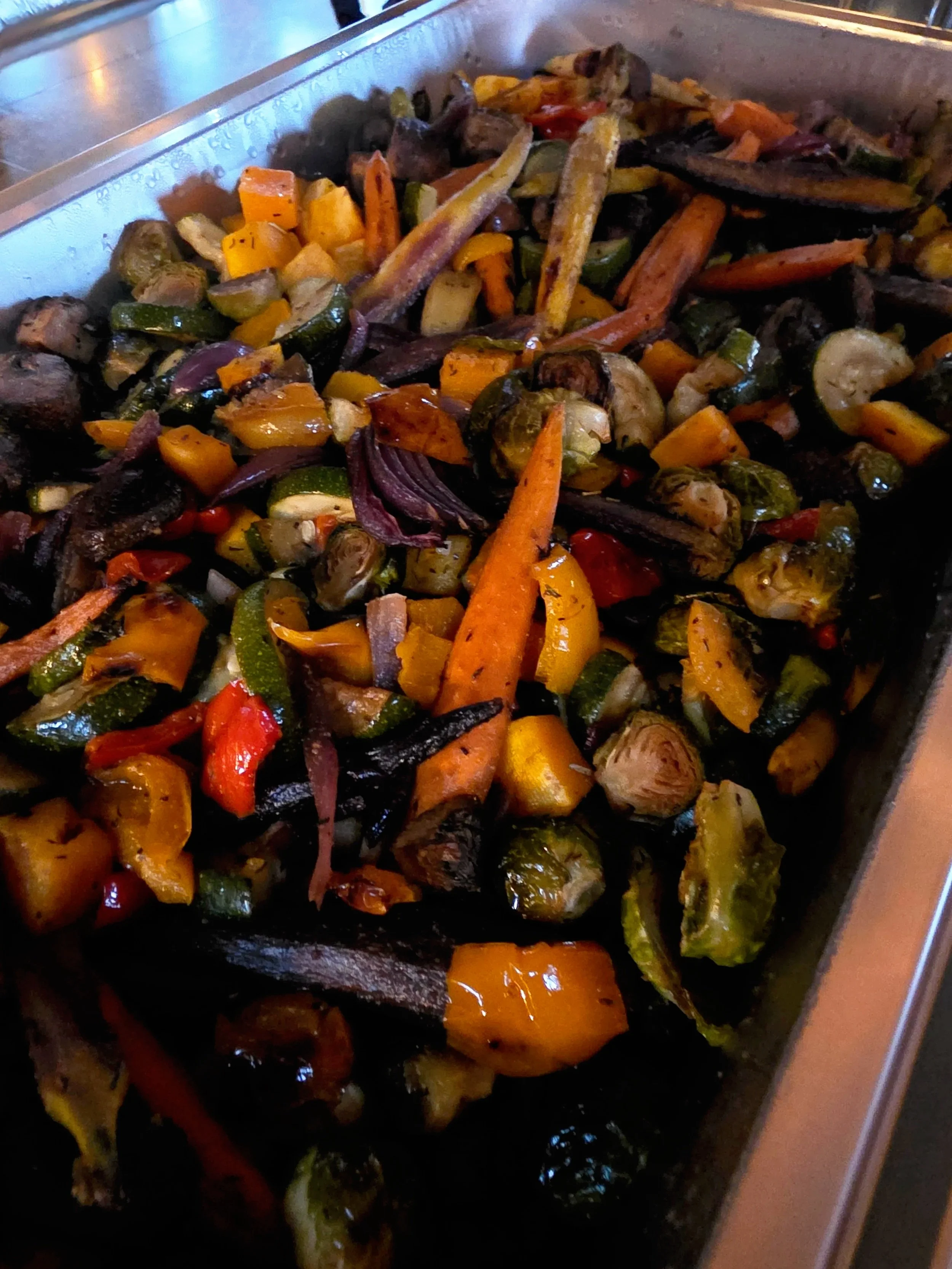 A tray filled with roasted mixed vegetables including carrots, zucchini, yellow squash, bell peppers, mushrooms, and eggplant.