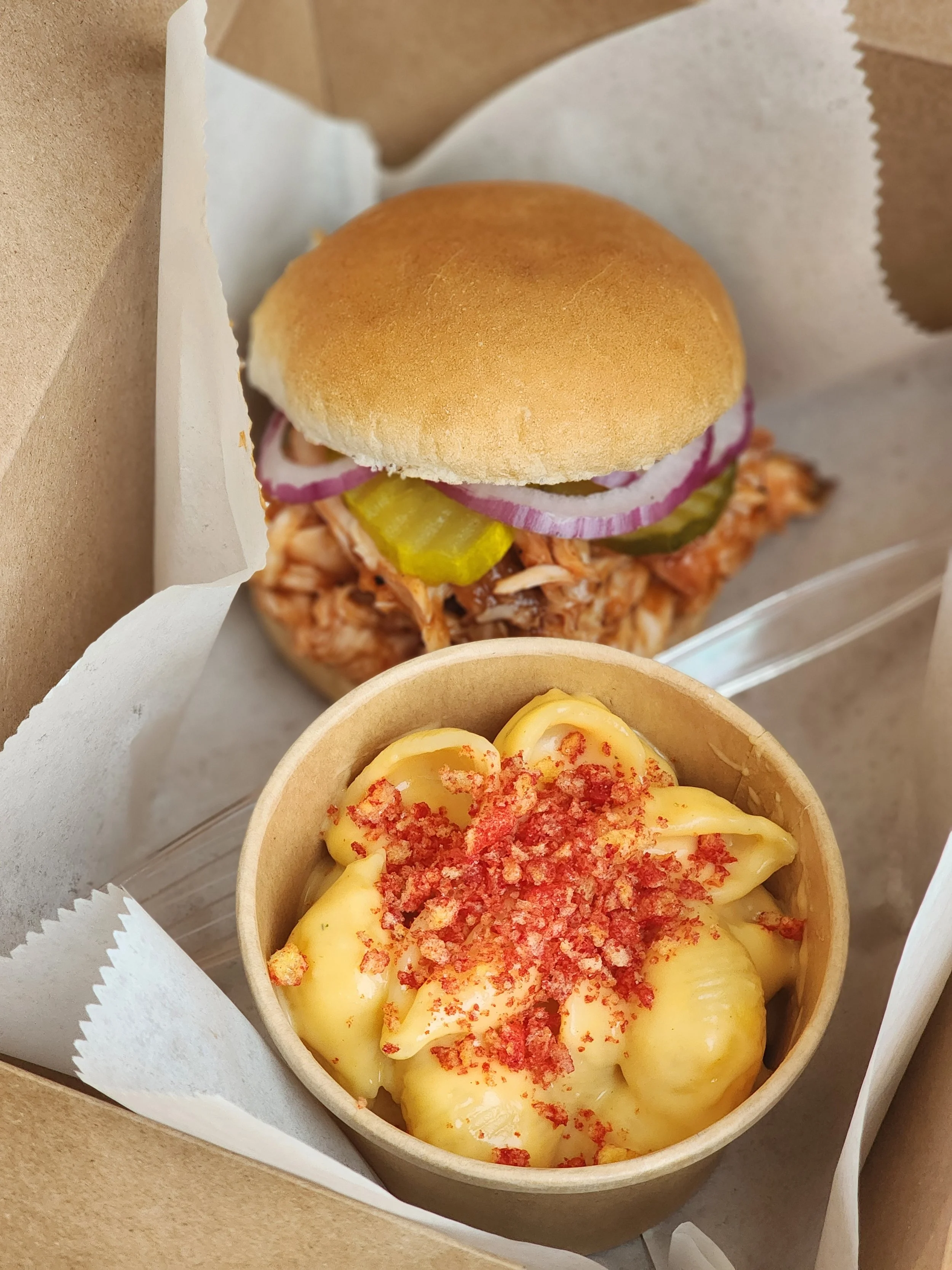 Close-up of a BBQ Sandwich and Macaroni and Cheese in a paper cup.