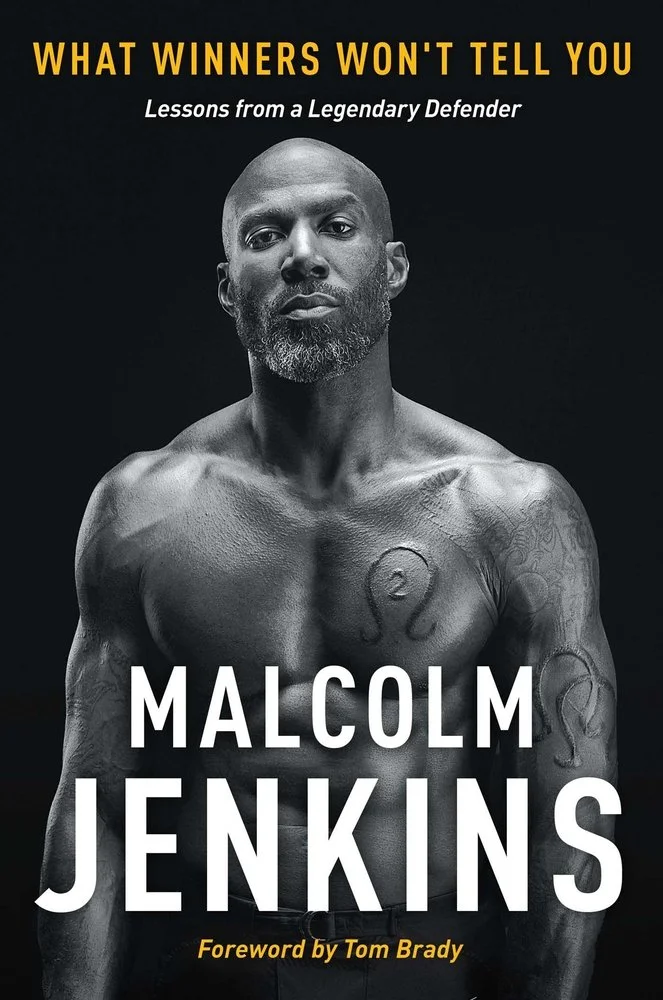 Book cover featuring a muscular, shirtless Black man with tattoos on his chest and arms, with a serious expression. Title at the top reads "What Winners Won't Tell You," and the author’s name "Malcolm Jenkins" is prominently displayed in large white letters in the center. The subtitle "Lessons from a Legendary Defender" appears below the title, with a foreword by Tom Brady noted at the bottom.