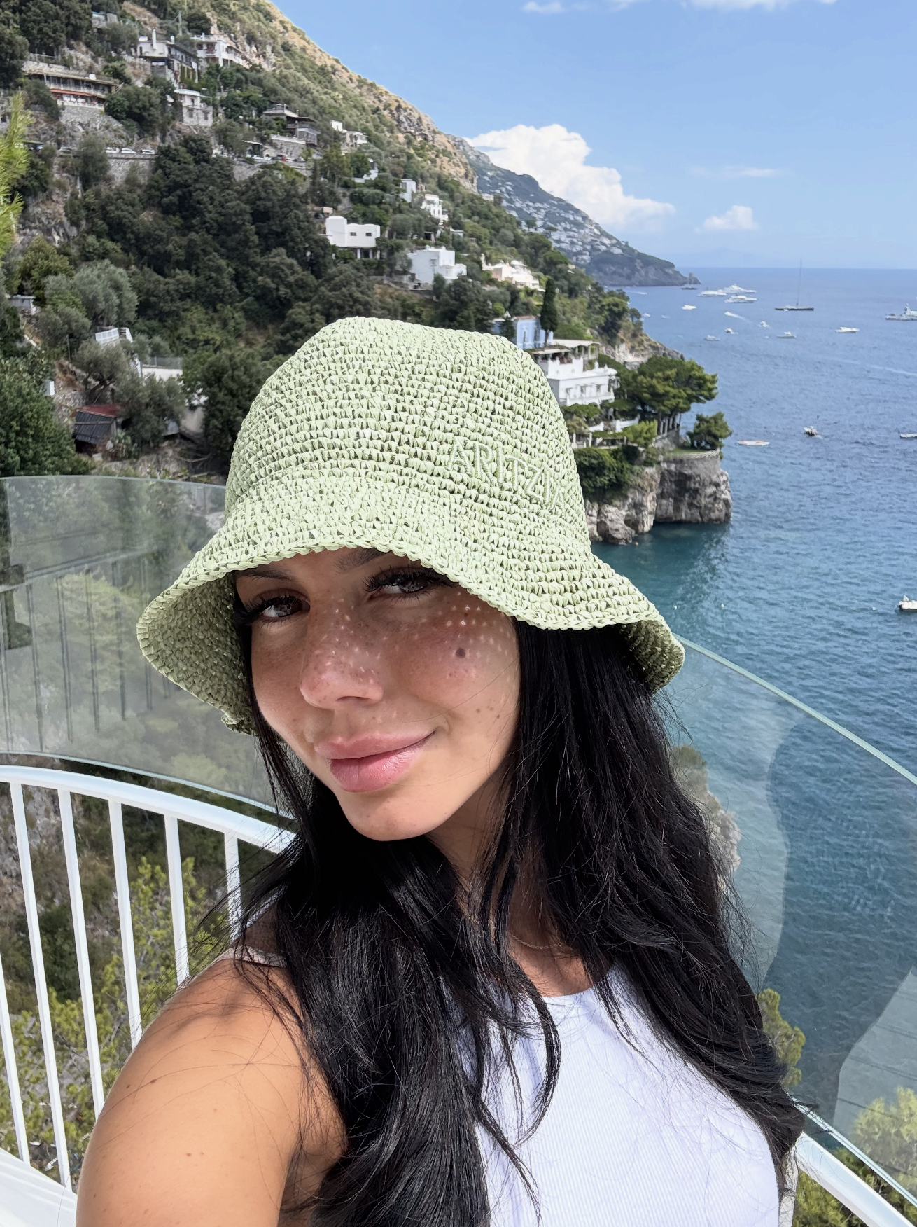A woman wearing a light green straw hat with