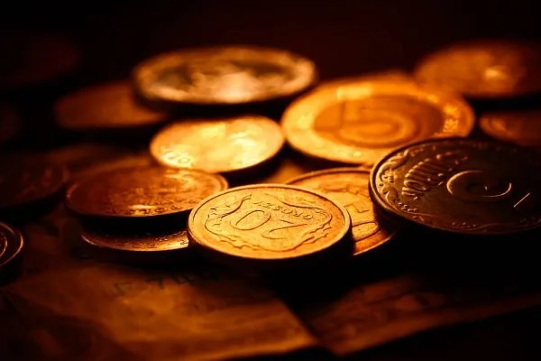 Monete d'oro e di bronzo sparse su una superficie scura