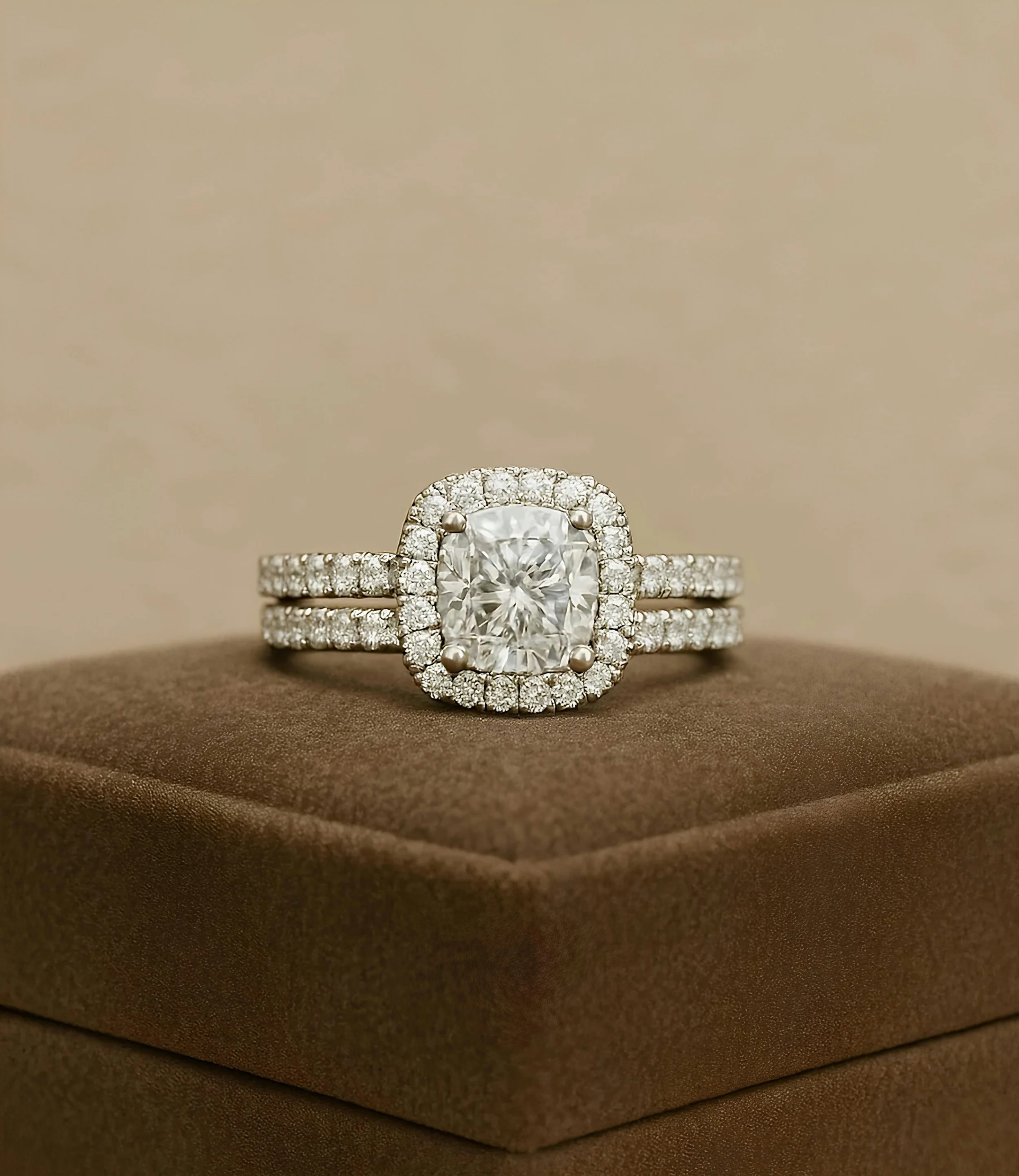Anello con diamante taglio cuscino e pavé su un portagioie marrone