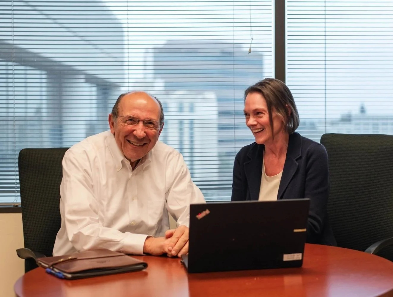 John Ranelli and JoAnne Jonte sitting at desk behind computer and smiling