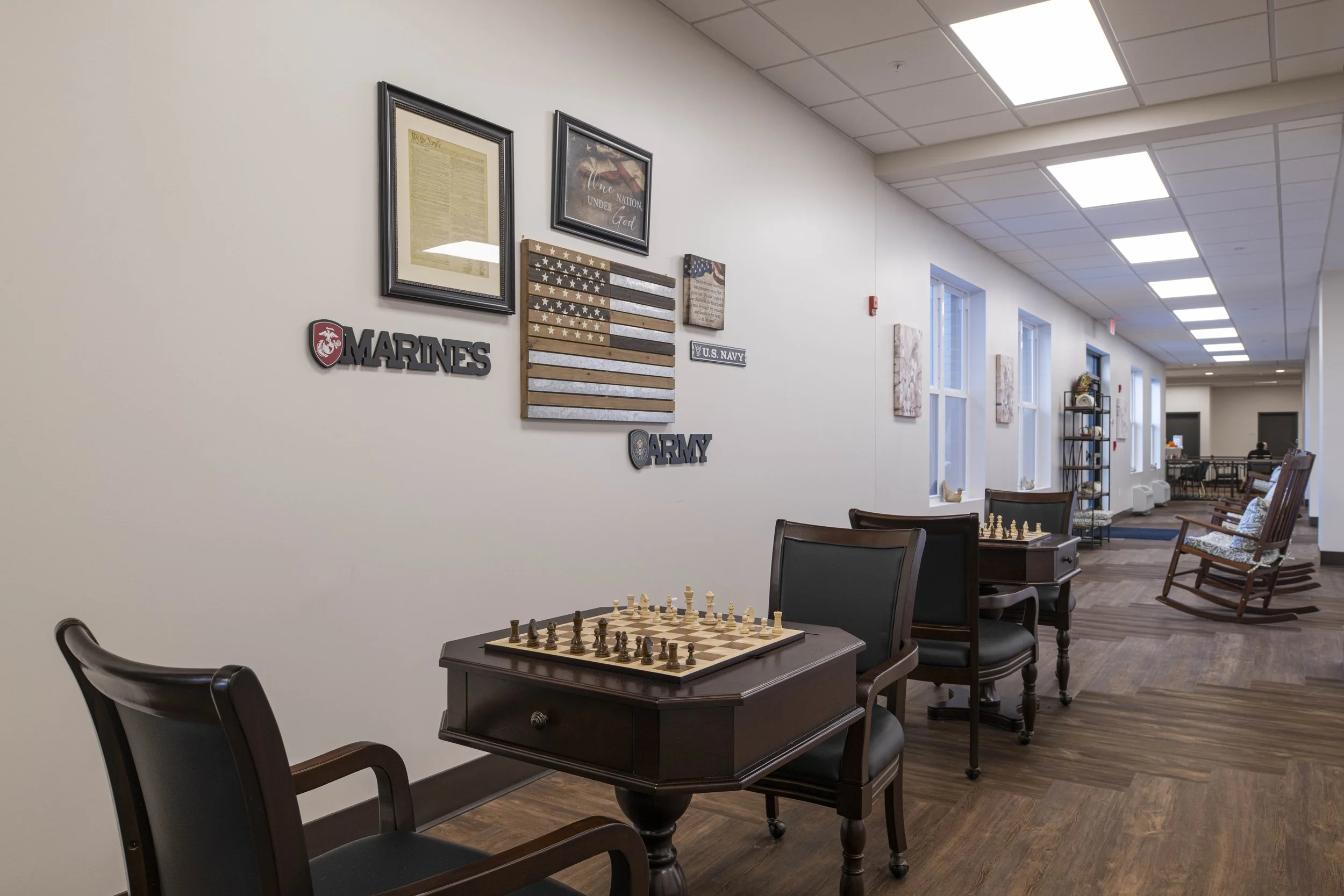 A hallway with chairs, tables, and chessboards, decorated with American flags, military-themed posters, and patriotic wall art.