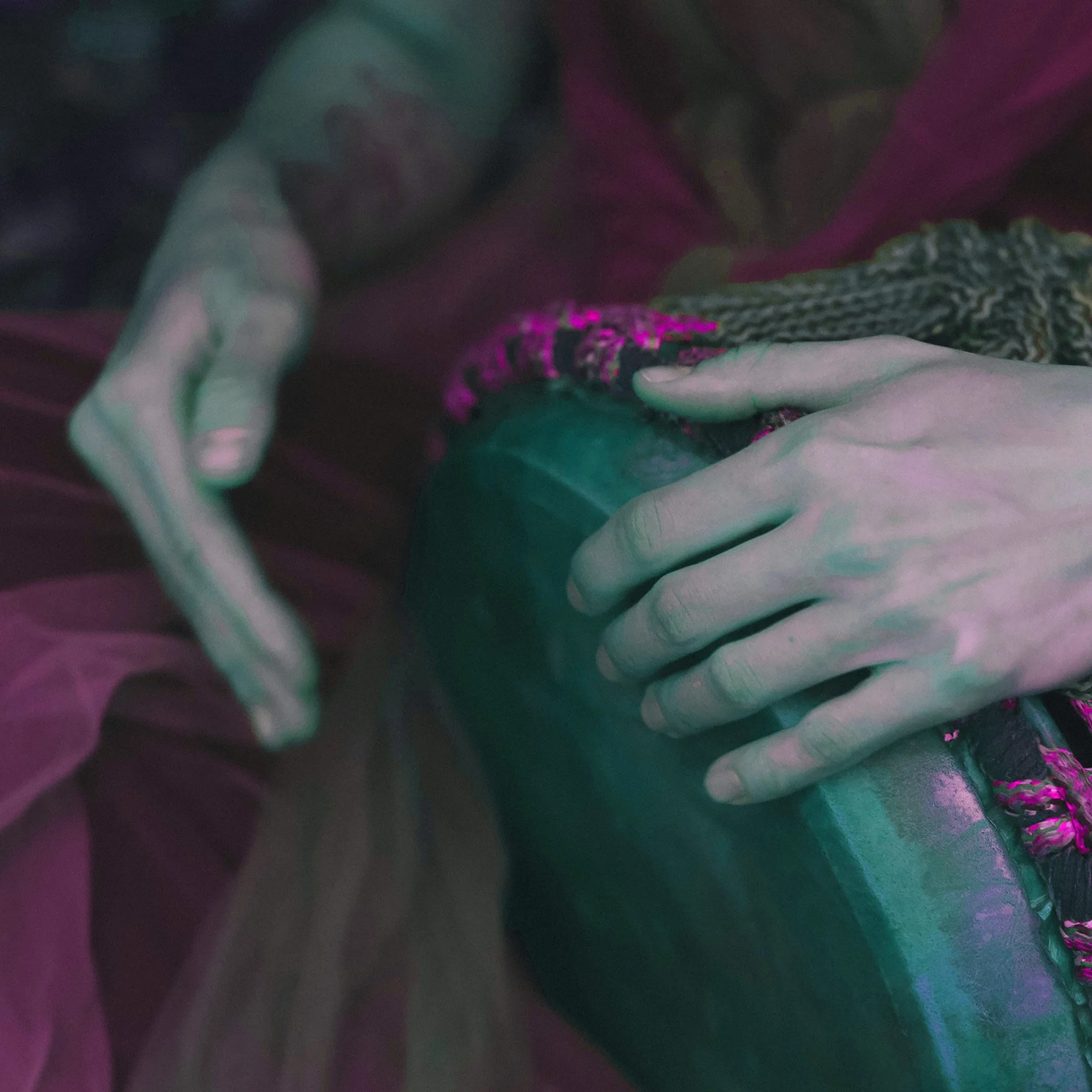 Personas tocando un instrumento, posiblemente un tambor, en un ambiente con iluminación de neón rosa y verde.