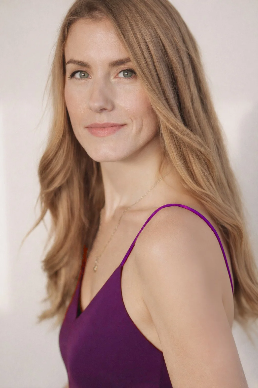 Retrato de una mujer con cabello largo, lacios, color castaño claro, usando un vestido morado y una cadena dorada con un colgante.