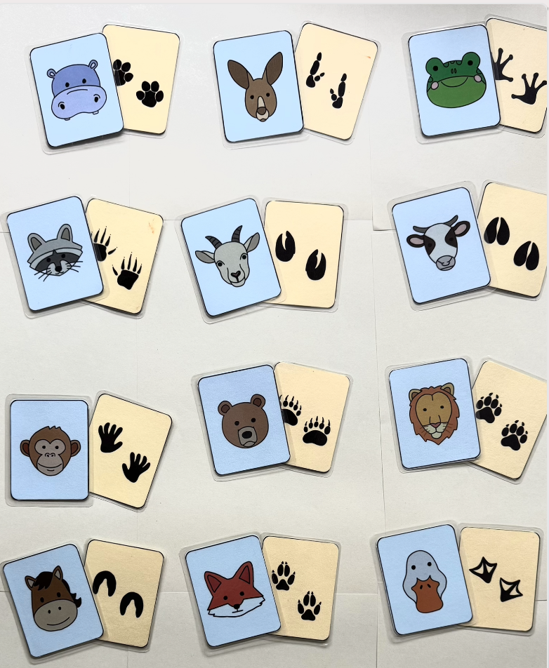 Animal-themed cards with matching paw print or handprint symbols on beige cards, including animals like a hippopotamus, kangaroo, frog, raccoon, goat, cow, chimpanzee, lion, horse, fox, and duck, arranged on a white surface.