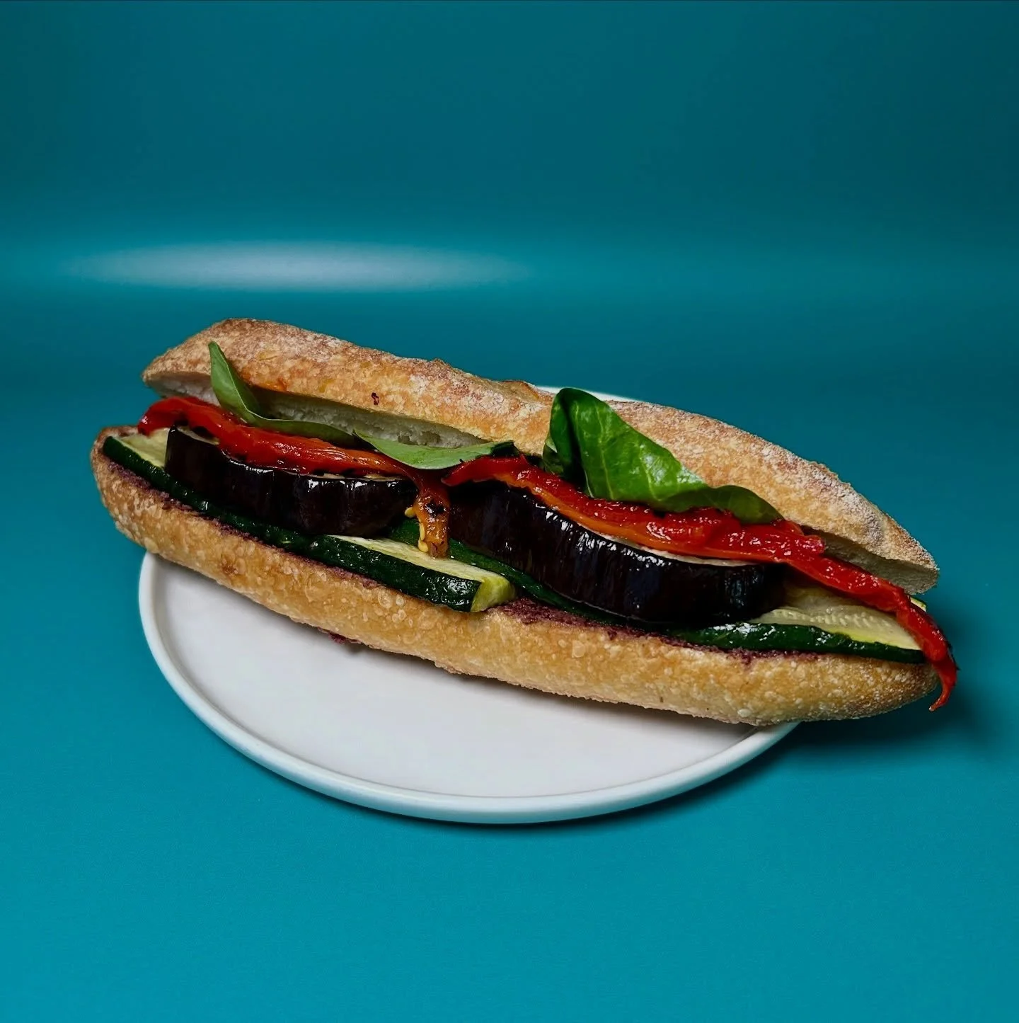The Mediterre is our new seasonal vegan sandwich. We build layers of smokey flavor by roasting the eggplant and zucchini, and adding in charred piquillo peppers. These roasted veggies sit on top of a savory, briny olive tapenade. Finished with leaves